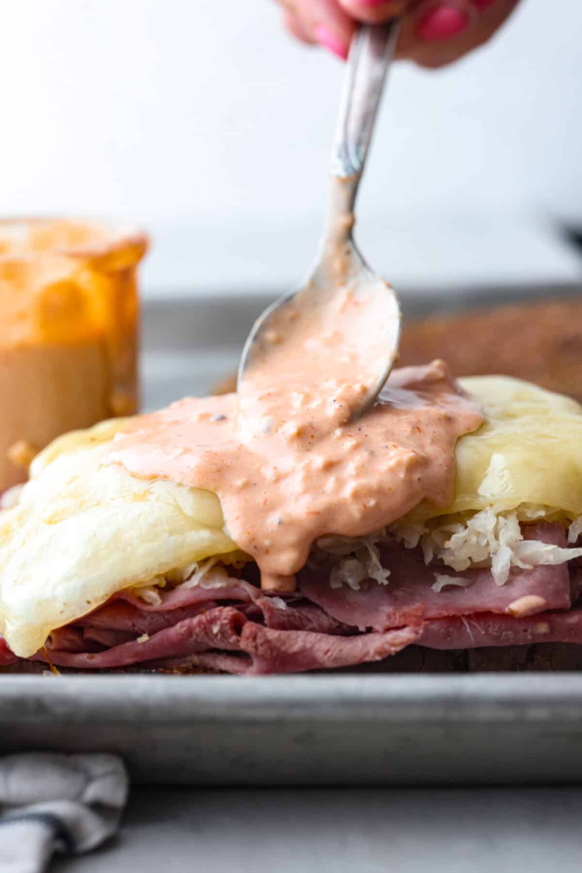 Homemade Russian dressing is a creamy and flavorful condiment perfect for sandwiches, burgers, and even as a dip. It's easy to make with simple ingredients and has the perfect balance of sweet, tangy, and spicy flavors. Drizzling the sauce over sandwich fixings.