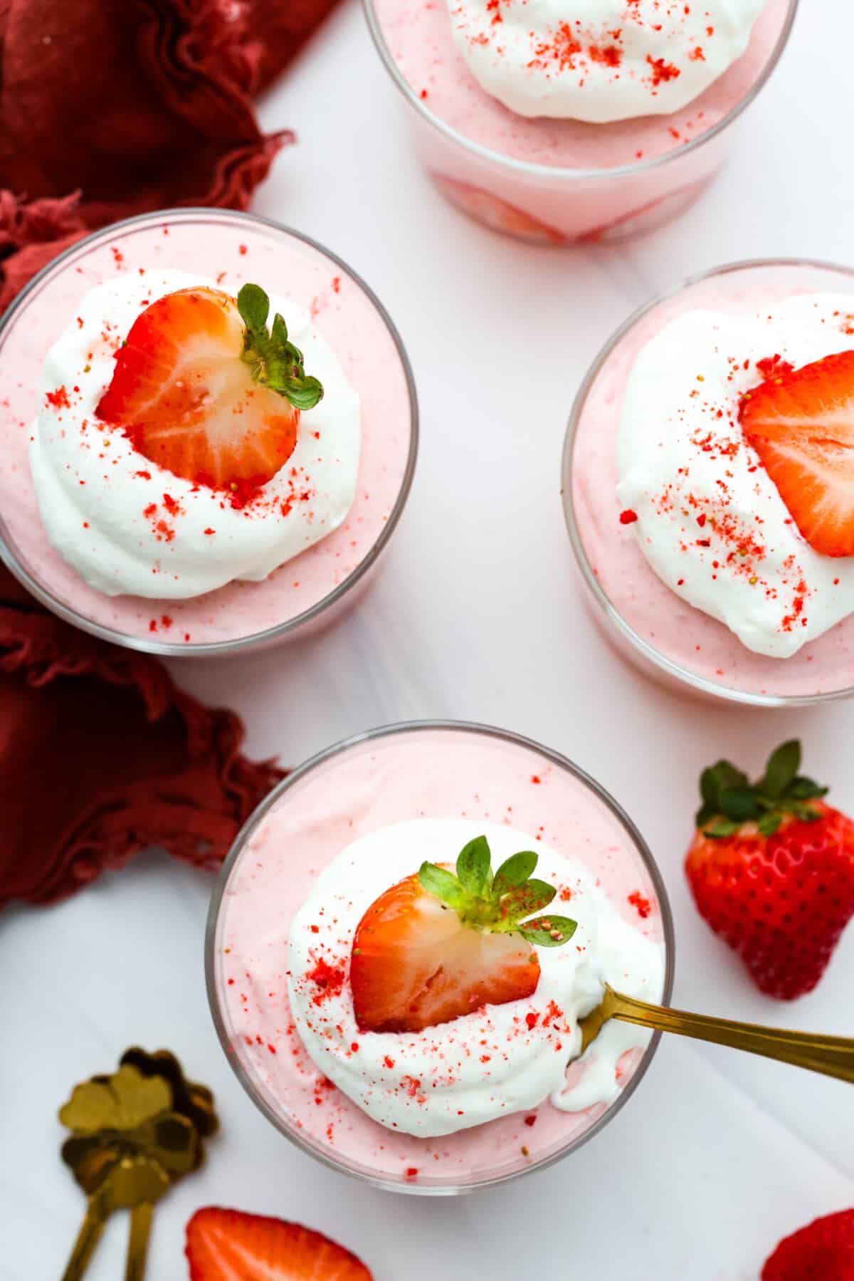 Deliciously sweet and creamy, this Strawberry Mousse is a dessert that looks impressive, yet is so easy to make. It tastes amazing, is bursting with fruity flavor, and would be the perfect treat for any occasion! Top-down view of glass cups filled with strawberry mousse.