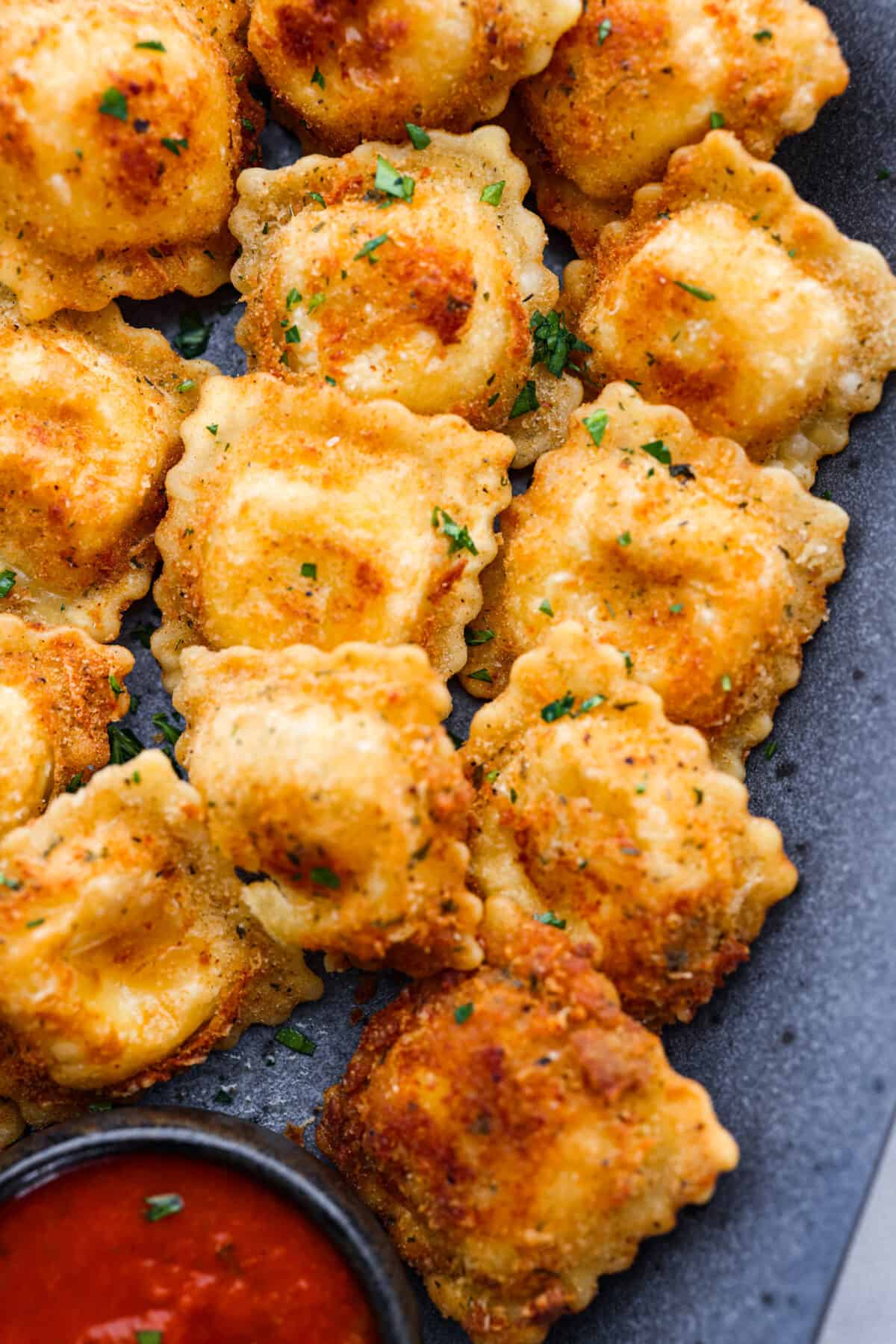 Tender ravioli coated in Italian breadcrumbs and parmesan cheese, toasted to golden brown perfection! Served with a side of marinara for dipping, this is one appetizer you donโt want to miss! Close-up of toasted ravioli.