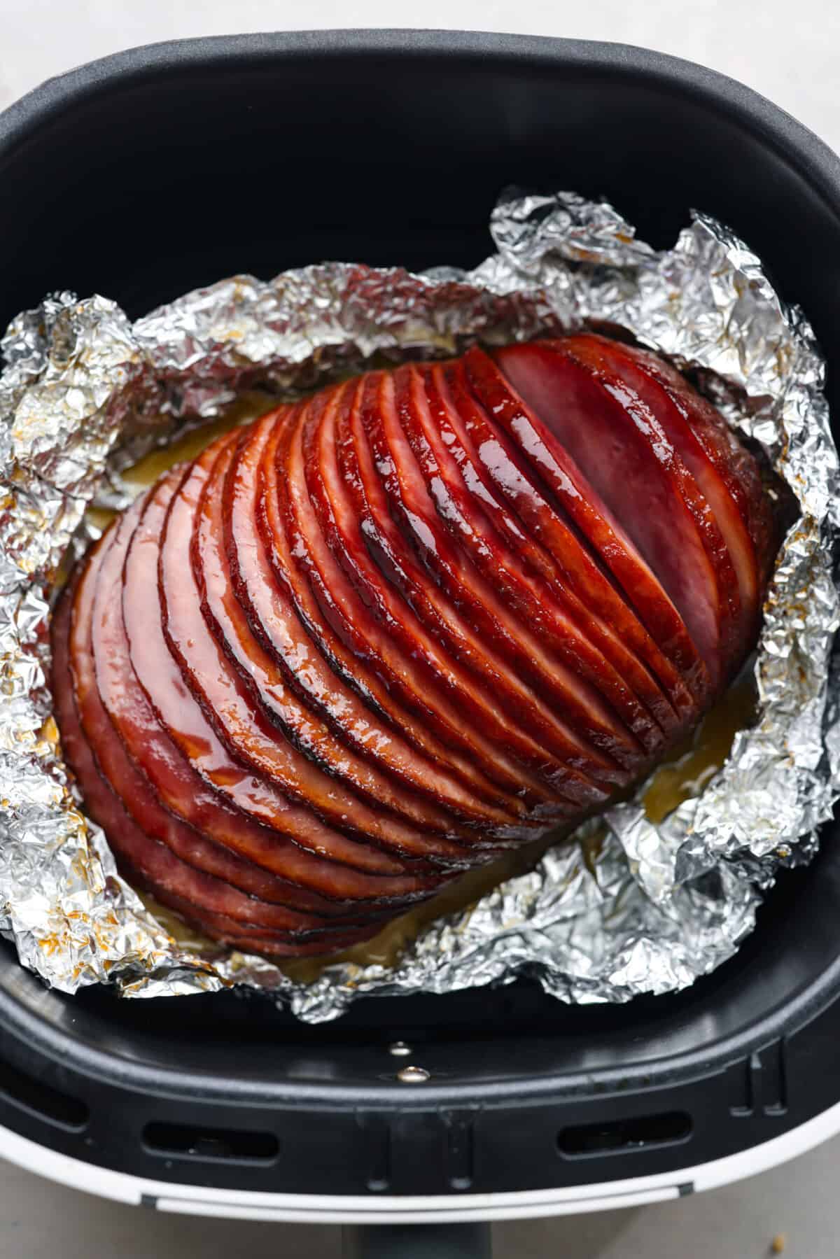 This air fryer ham is moist and flavorful with the most delicious caramelized honey glaze! It's super easy to make and tastes so incredible, you'll never want to cook ham any other way! Your friends and family will all be asking for the recipe! Sliced ham in an air fryer.