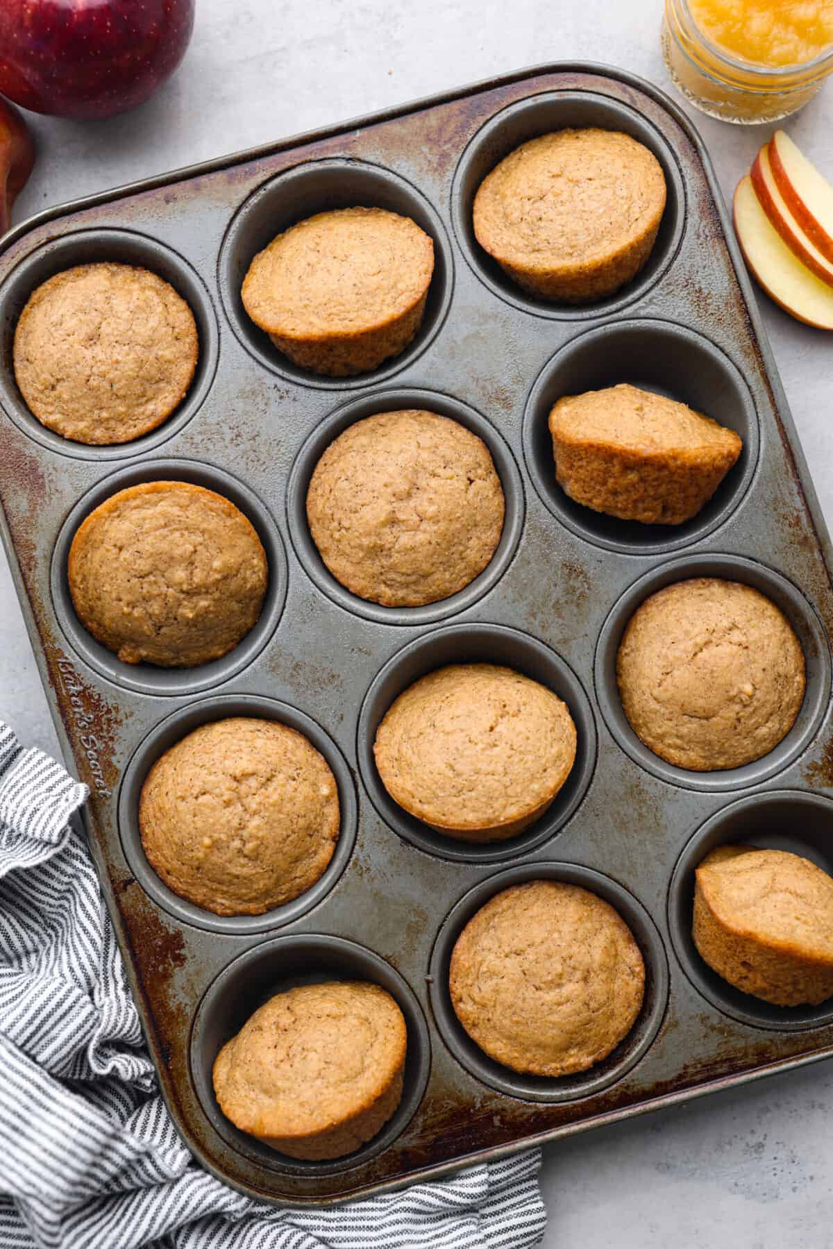 I see a batch of sweet and ultra-moist applesauce muffins in your future! Theyโre so delicious and made with all-natural sugars. The perfect breakfast, snack, dessert, you name it! Top-down view of baked muffins in a muffin tin.