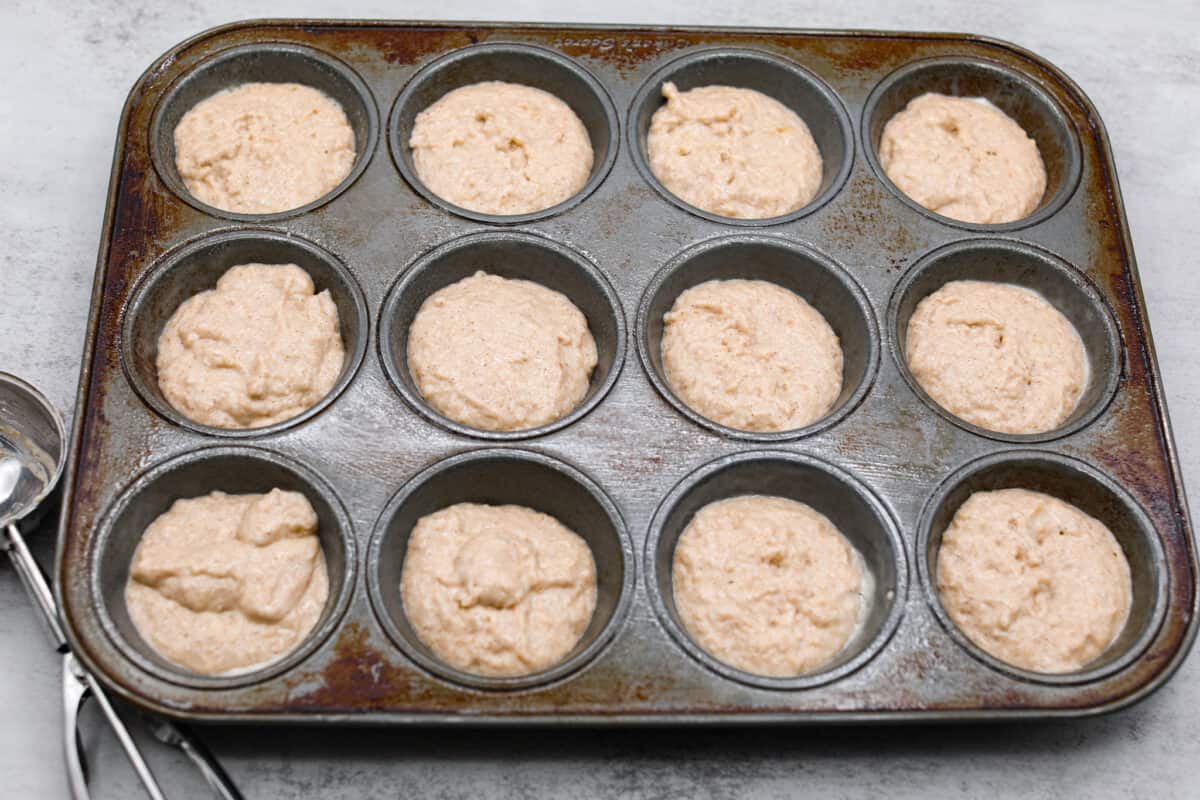 I see a batch of sweet and ultra-moist applesauce muffins in your future! Theyโre so delicious and made with all-natural sugars. The perfect breakfast, snack, dessert, you name it! The applesauce muffin batter being added to a muffin tin.