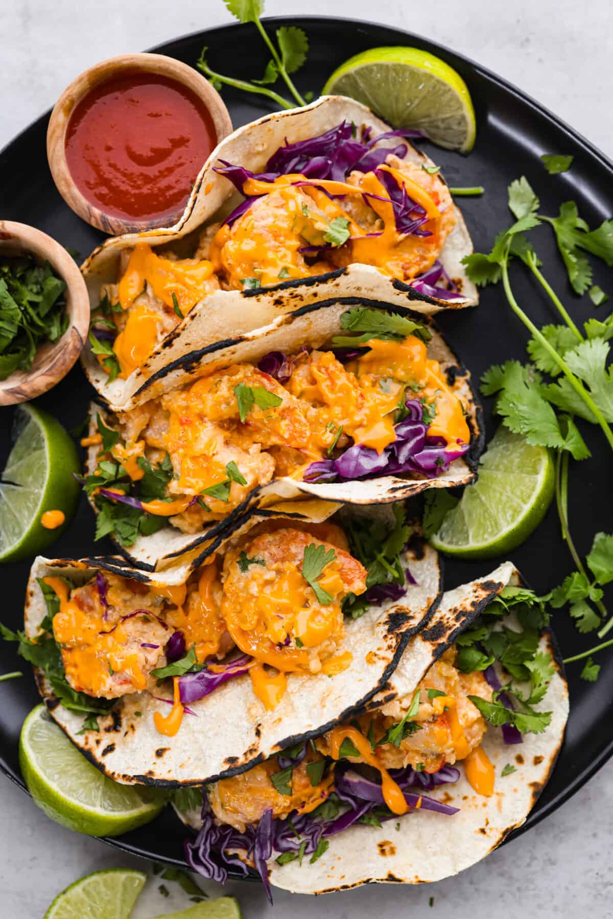 These Bang Bang Shrimp Tacos are made with deliciously crunchy shrimp cooked to perfection and coated in a special sauce that's just bursting with flavor! It's a meal that's sure to impress. Bang Bang Shrimp Tacos on a plate.