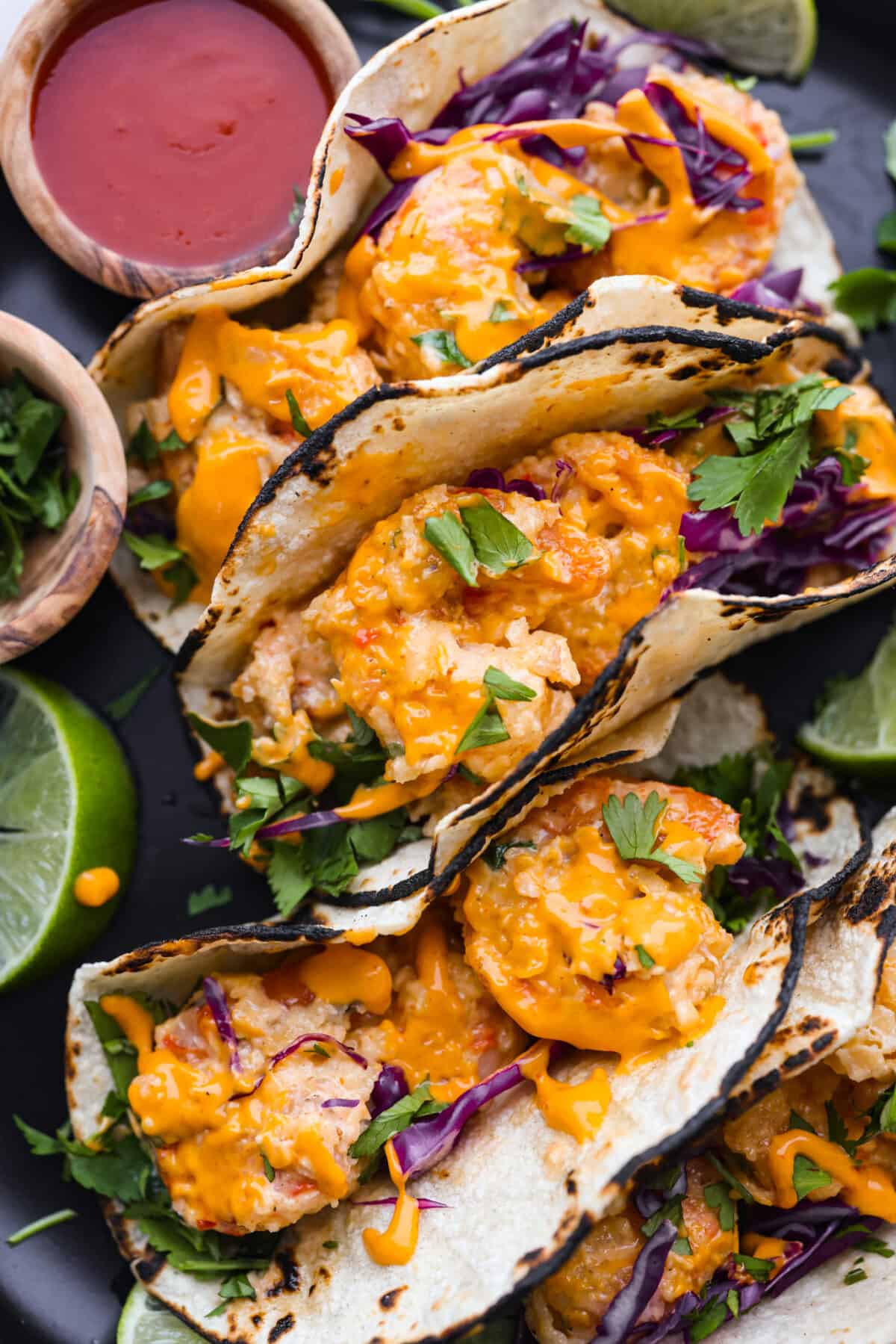 These Bang Bang Shrimp Tacos are made with deliciously crunchy shrimp cooked to perfection and coated in a special sauce that's just bursting with flavor! It's a meal that's sure to impress. A close up of bang bang shrimp tacos.