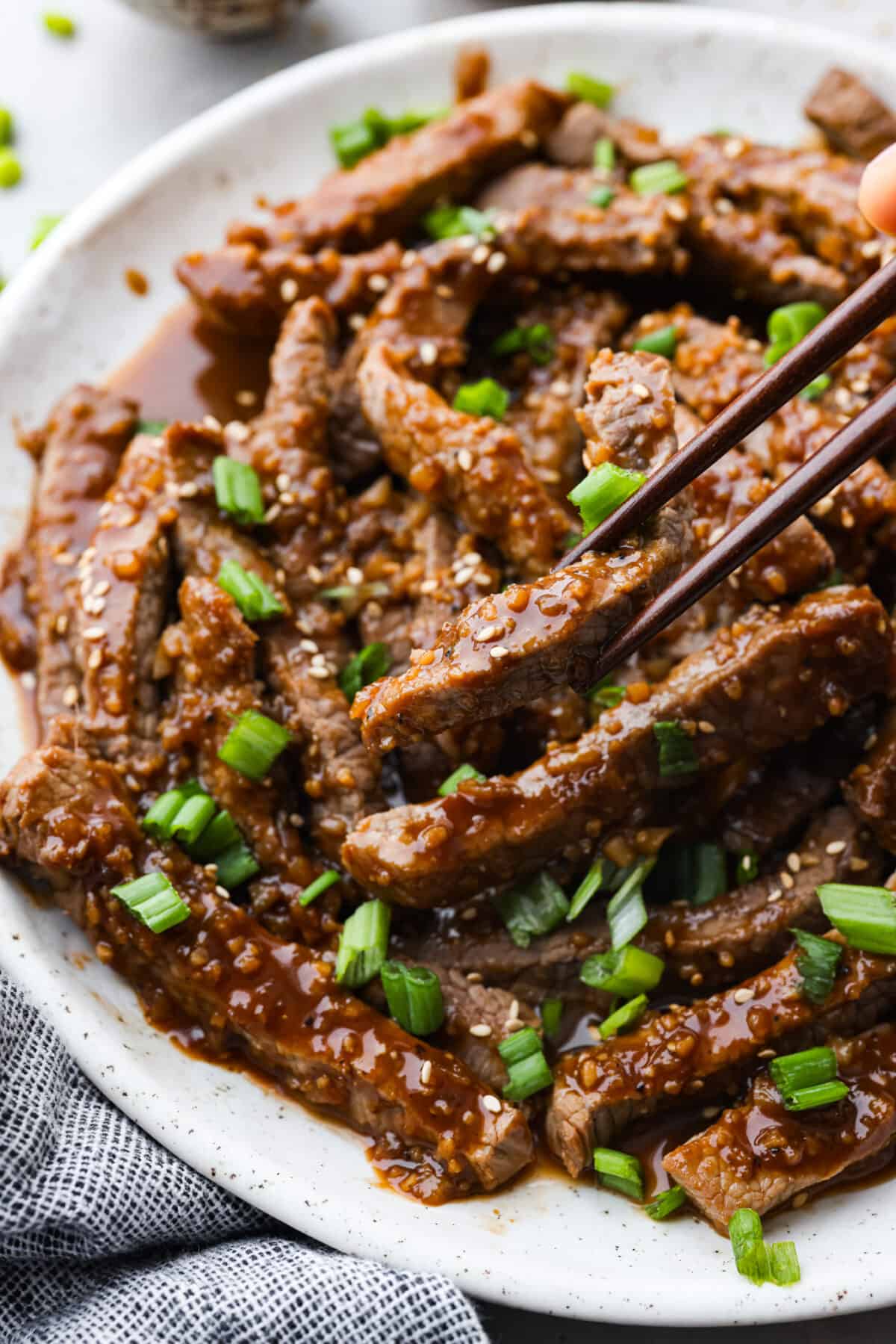 This amazing Korean Beef Bulgogi is easier than you think and doesn't need any fancy ingredients. It's a quick dinner that creates the most melt-in-your-mouth, flavorful beef! Perfect for busy families, it's ready in 45 minutes with only 10 minutes of actual prep and cook time. Closeup of bulgogi being picked up with chopsticks.