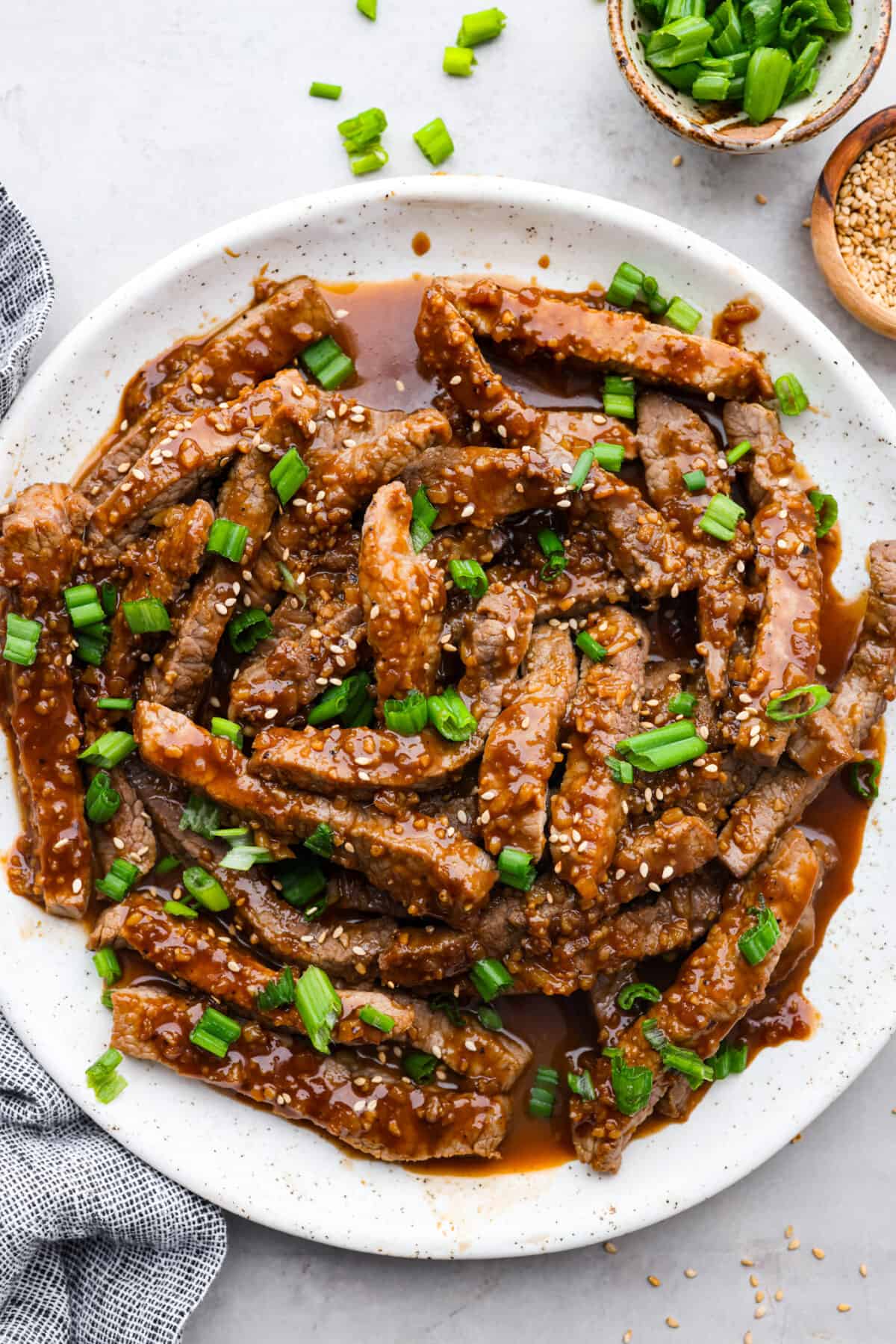 This amazing Korean Beef Bulgogi is easier than you think and doesn't need any fancy ingredients. It's a quick dinner that creates the most melt-in-your-mouth, flavorful beef! Perfect for busy families, it's ready in 45 minutes with only 10 minutes of actual prep and cook time. Strips of beef bulgogi served on a white plate.