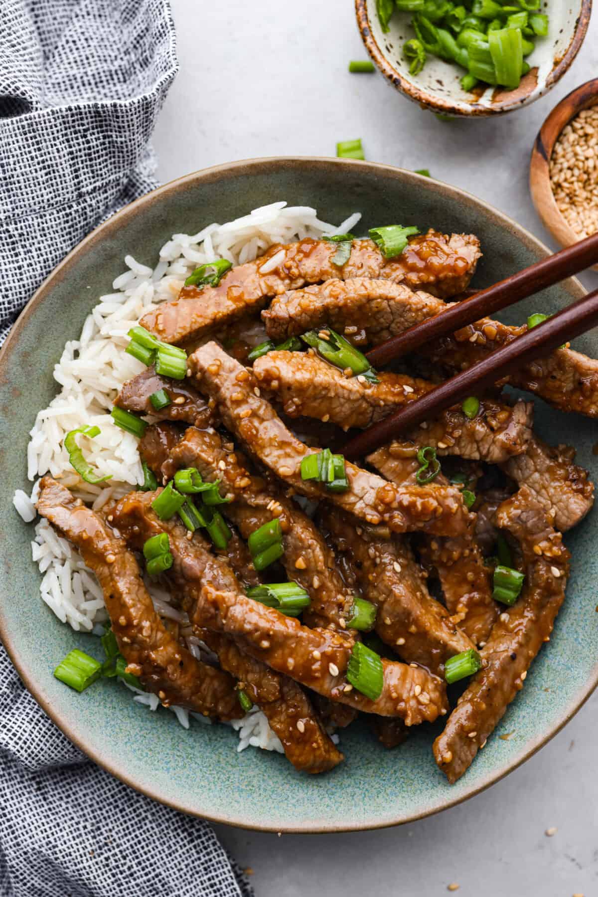 This amazing Korean Beef Bulgogi is easier than you think and doesn't need any fancy ingredients. It's a quick dinner that creates the most melt-in-your-mouth, flavorful beef! Perfect for busy families, it's ready in 45 minutes with only 10 minutes of actual prep and cook time. Korean beef bulgogi served over white rice in a stoneware bowl.