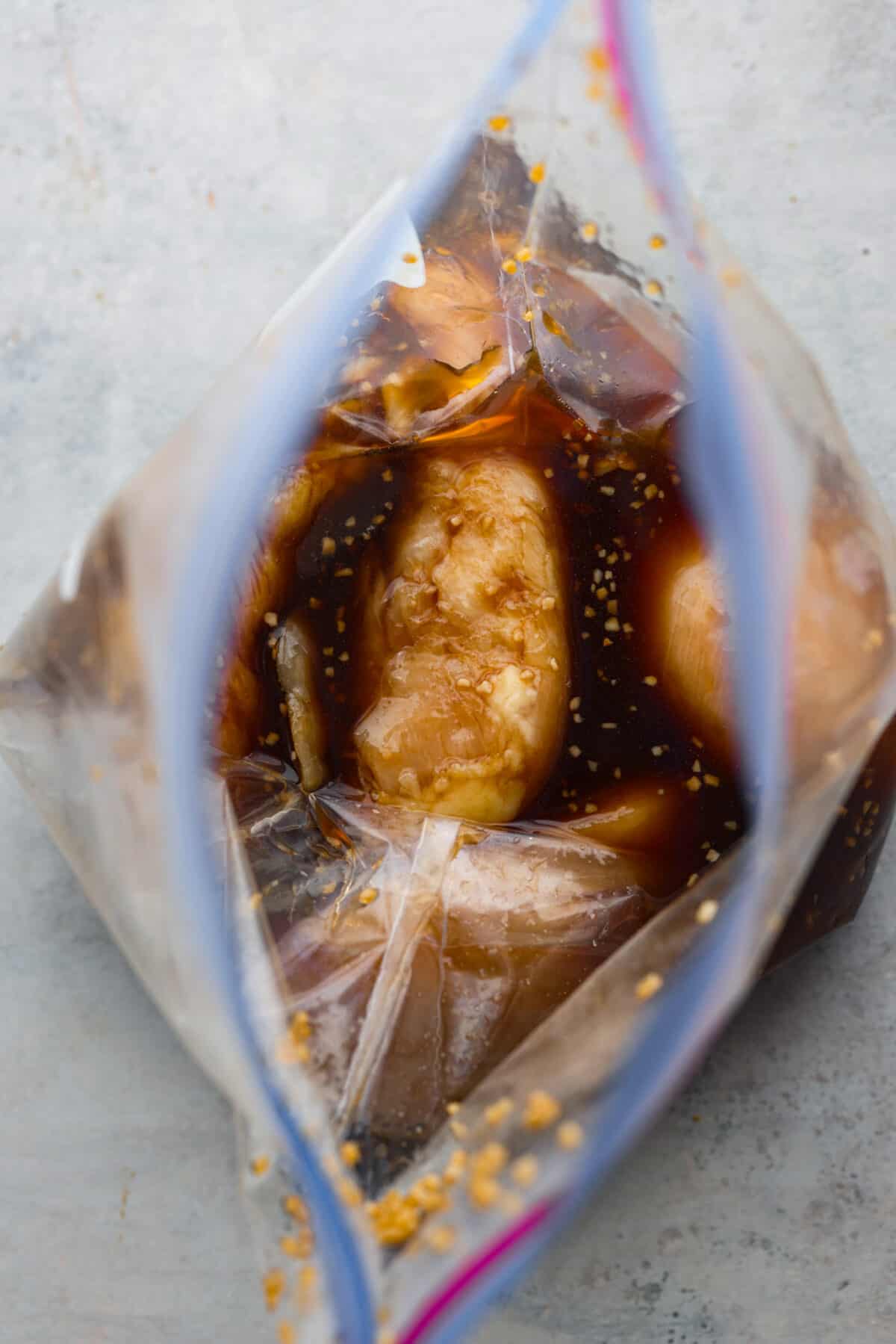 This delicious bourbon marinade will add wonderful depth of flavor and tenderize any meat you're cooking, from steak to chicken! This recipe uses ingredients like brown sugar, Worcestershire sauce, apple cider vinegar, garlic and bourbon to infuse each piece of meat with the perfect savory, sweet and tangy flavor. Top-down view of marinating chicken breasts in a ziploc bag.