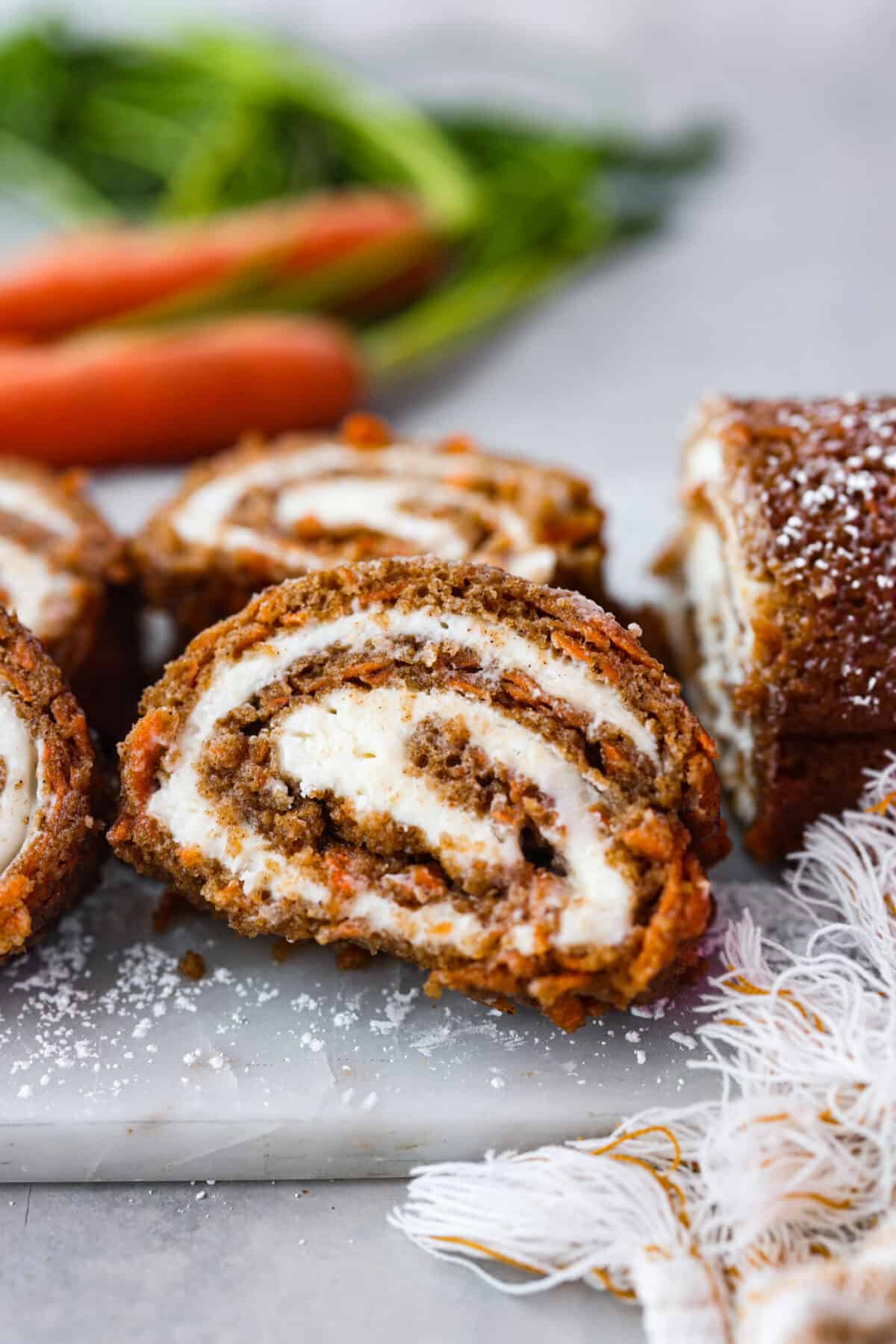 Stunning carrot cake roll is a wonderful joining of deliciously spiced carrot cake, swirled with tangy cream cheese frosting. It looks fancy but it's easy to make and so perfect for Easter and Spring themed celebrations! Hero image of a slice of a carrot cake roll.