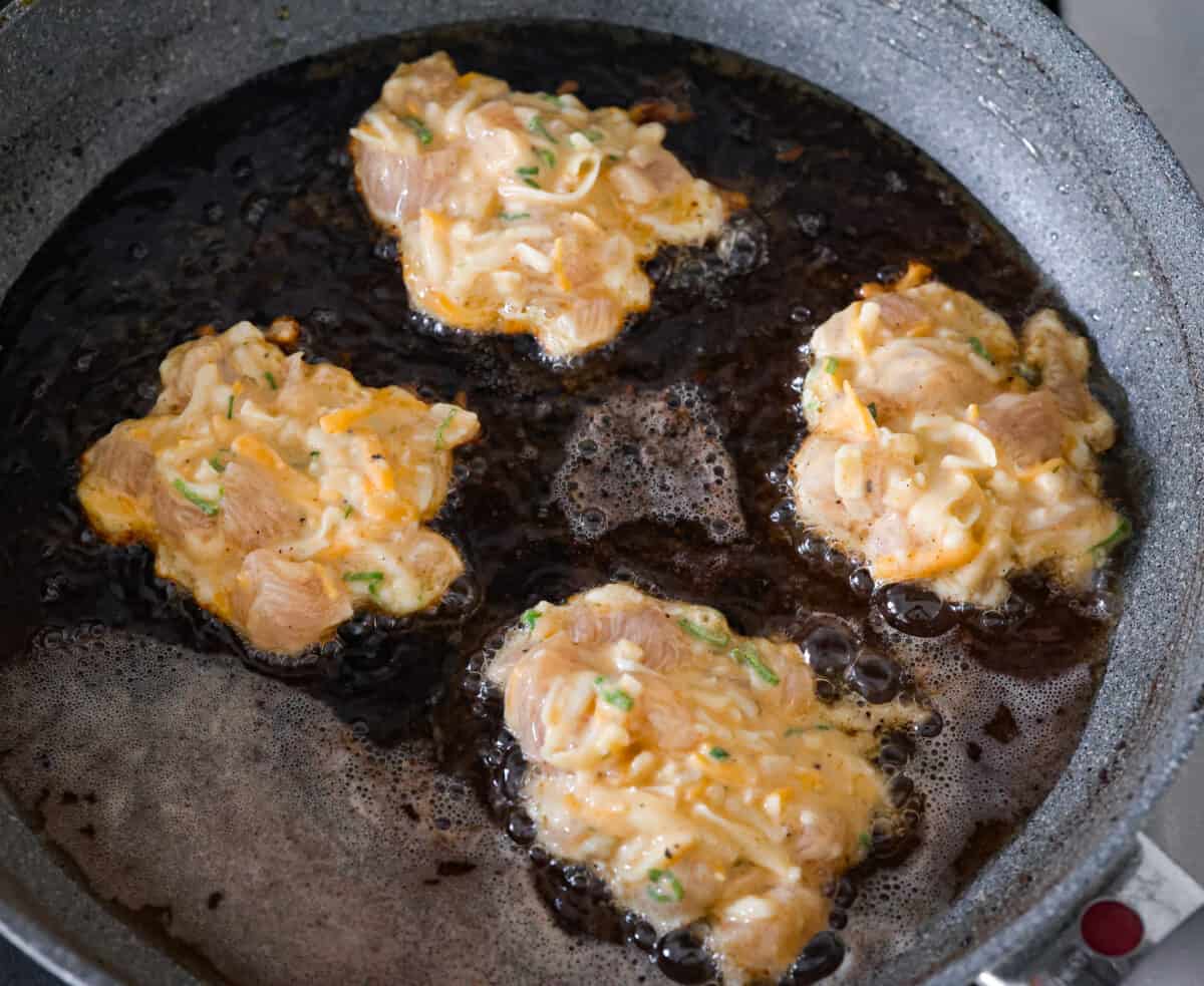 Flavorful chicken fritters are warm and crispy crowd favorites! Simply mix tender pieces of chicken breast and shredded cheese with a seasoned batter and pan-fry to golden brown perfection. Serve them with your favorite sauce and wait for all the rave reviews from your family! Chicken fritters being fried