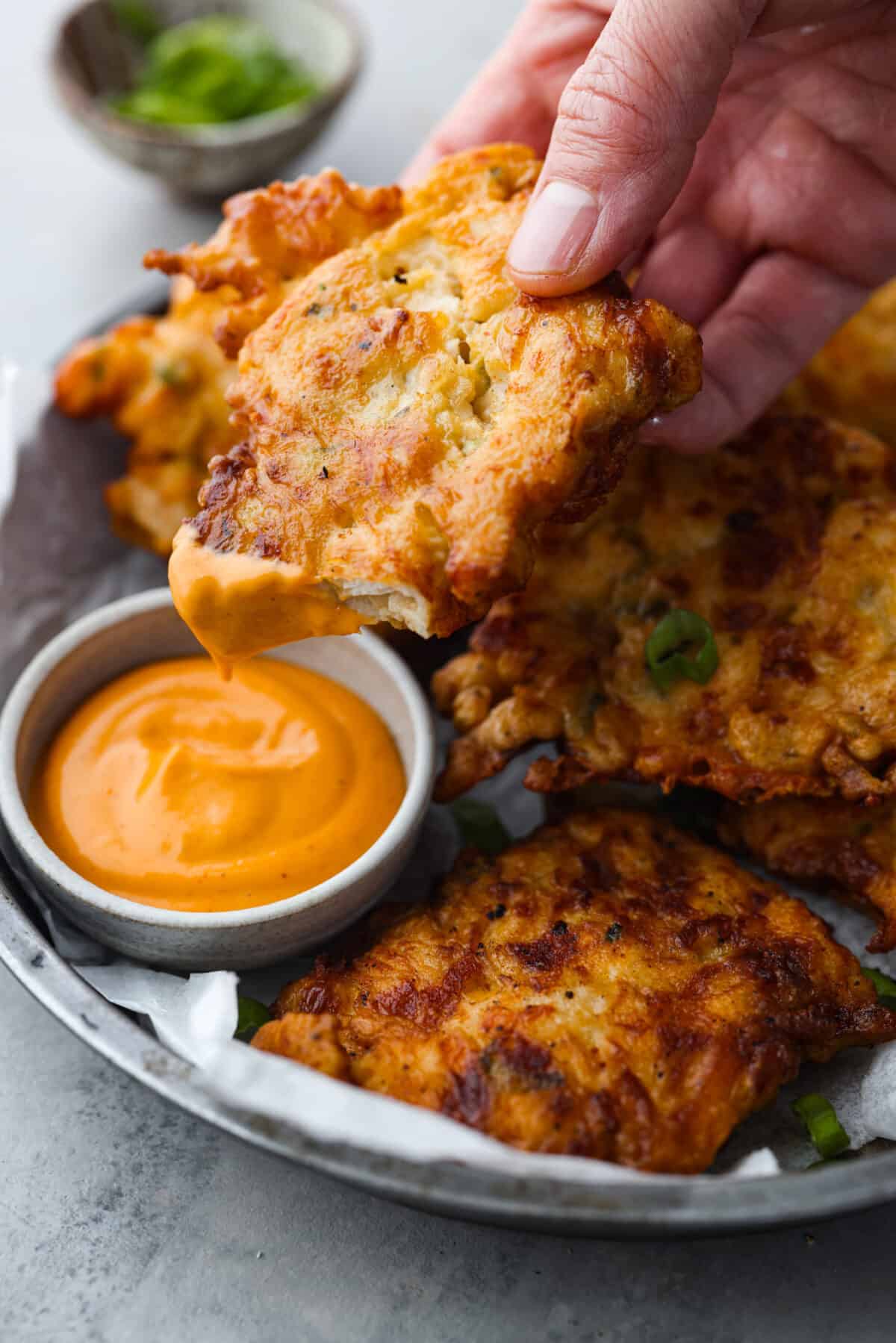 Flavorful chicken fritters are warm and crispy crowd favorites! Simply mix tender pieces of chicken breast and shredded cheese with a seasoned batter and pan-fry to golden brown perfection. Serve them with your favorite sauce and wait for all the rave reviews from your family! Dipping the chicken into a creamy orange sauce