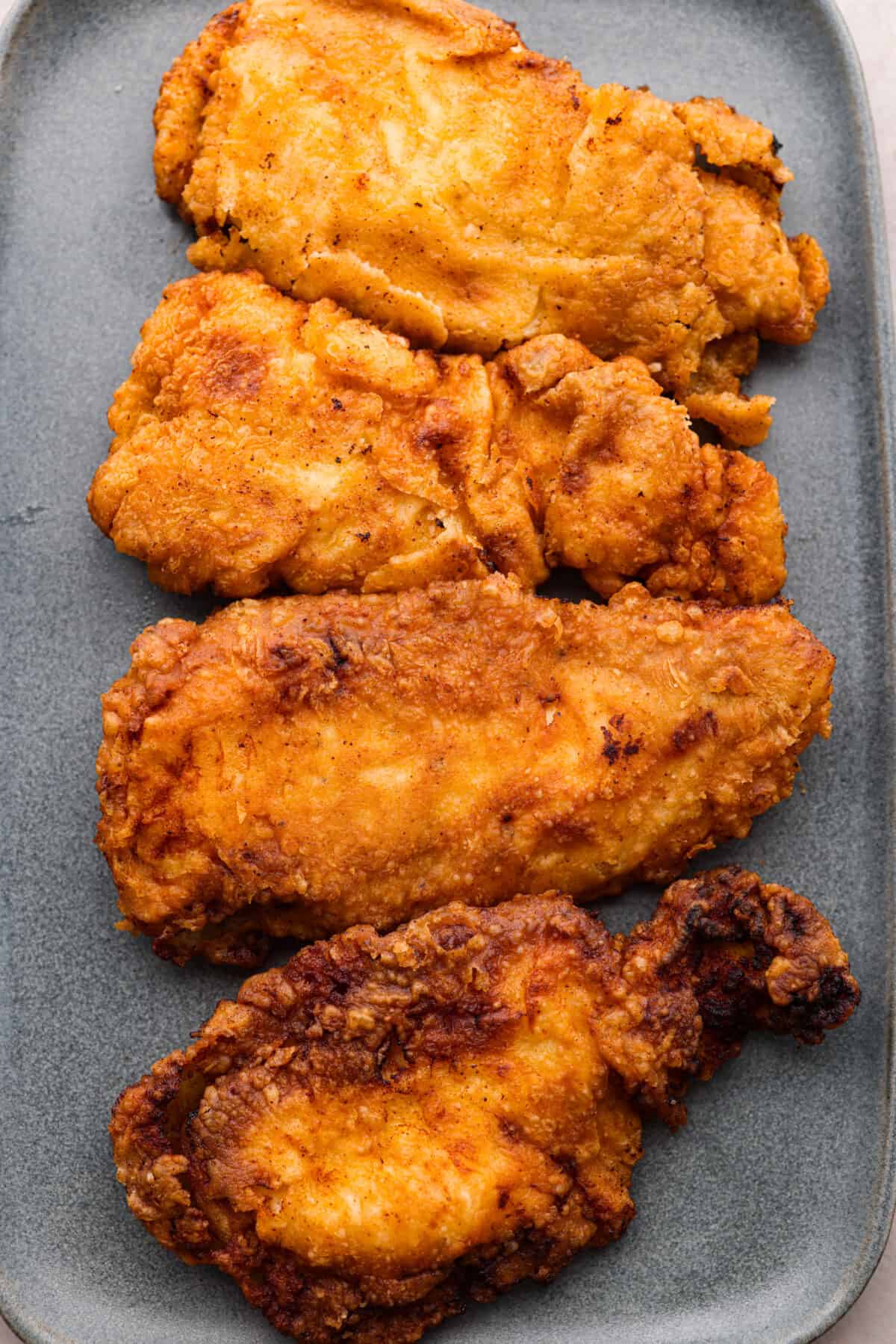 Bring all the best things about Southern cooking to your dinner table with this country fried chicken recipe! The result? Golden, crispy goodness smothered in savory homemade gravy. Top-down view of 4 country fried chicken cutlets.