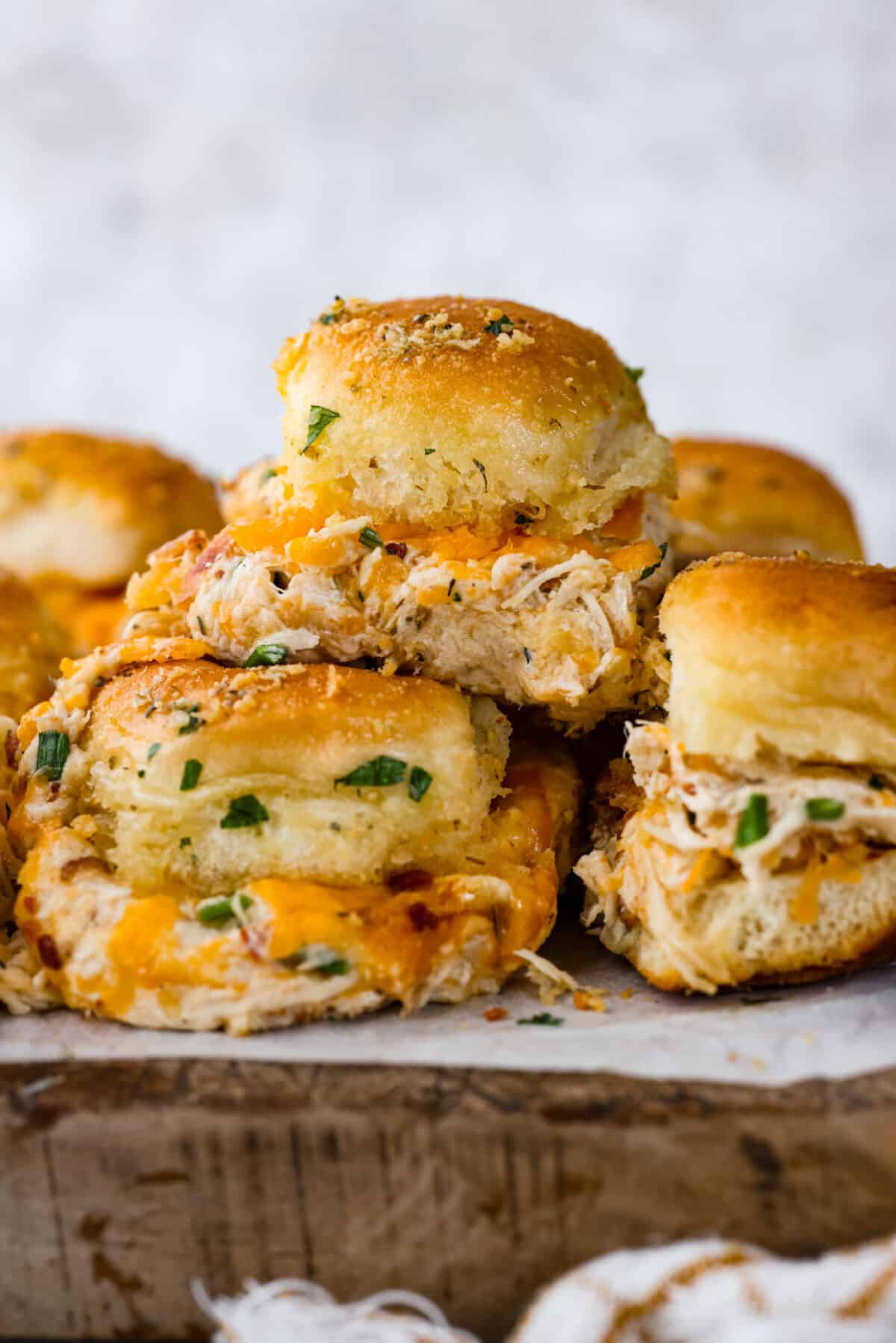 Hawaiian sweet rolls topped with creamy ranch chicken and bacon, brushed with a buttery parmesan glaze and then toasted to golden perfection! A stack of crack chicken sliders.