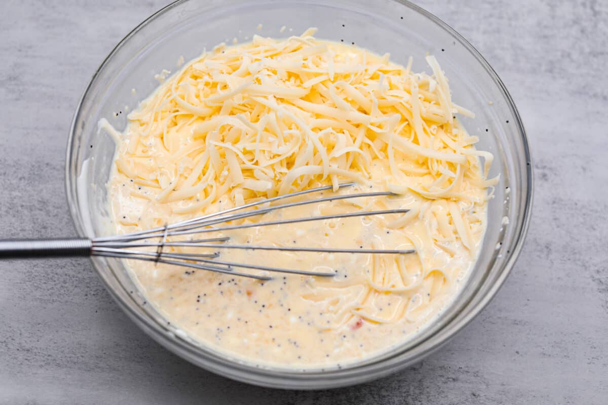 Wake up to the tasty flavors of this everything bagel casserole! It's made with everything bagels and seasoning, sausage, eggs, cream cheese, and gruyère cheese. The result is a creamy and savory breakfast casserole that everyone will devour! Second process photo of the eggs and cheese added to the milk mixture.