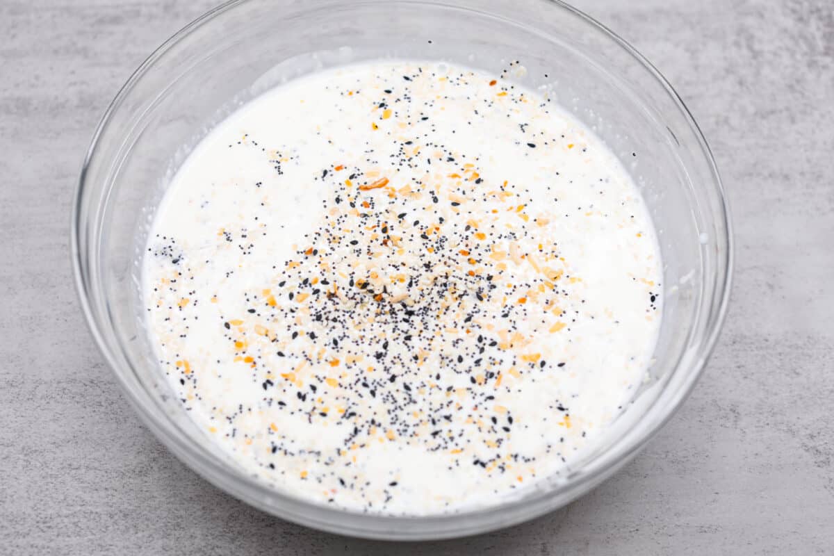 Wake up to the tasty flavors of this everything bagel casserole! It's made with everything bagels and seasoning, sausage, eggs, cream cheese, and gruyère cheese. The result is a creamy and savory breakfast casserole that everyone will devour! First process photo of the milk mixture in a bowl.