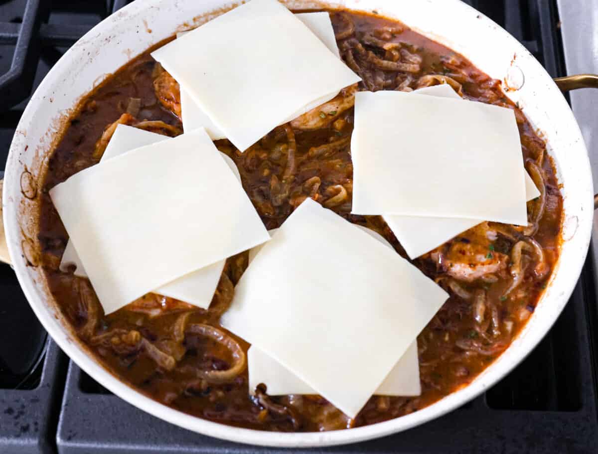 French Onion Pork Chops have all of the wonderful flavors of the classic soup in pork chop form! Caramelized onions and seared pork chops are joined with a savory sauce and two types of cheese for an amazing meal. Everything is cooked in one pan for a quick and easy weeknight dinner! Pork chops topped with cheese slices, before melting