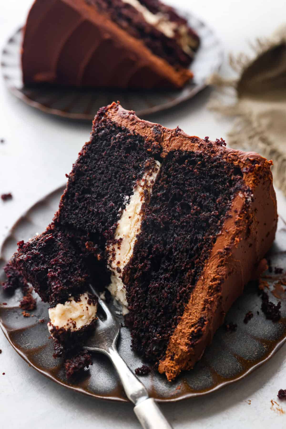 Celebrate St. Patrickโs Day (or any day) with this delicious Guinness Chocolate Cake! Itย has the most wonderful fudgy flavor and tender texture that is complemented by a Bailey's buttercream filling and a rich ganache frosting. A slice of chocolate Guinness cake on a scalloped plate.