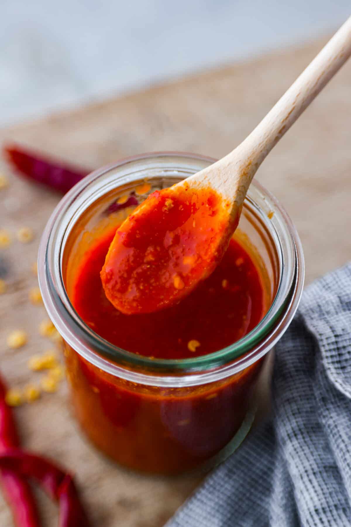 If hot sauce is something you use a lot in your kitchen, you have to try this homemade version! Tweak it to your liking then use it to upgrade all of your favorite dishes! Homemade hot sauce in glass jar, being mixed with a wooden spoon.