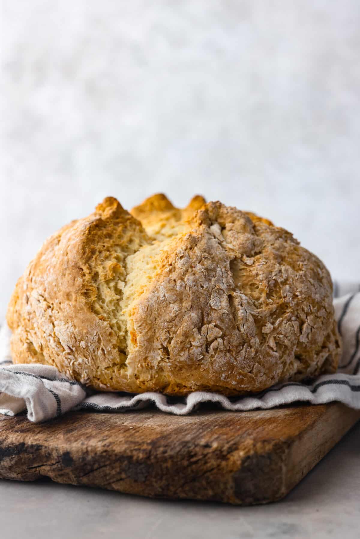 This Irish soda bread recipe uses just 4 pantry staples for a warm, crusty loaf that's perfect for slathering with butter and jam, or soaking up your favorite soup. No kneading required! A whole loaf of baked Irish soda bread.