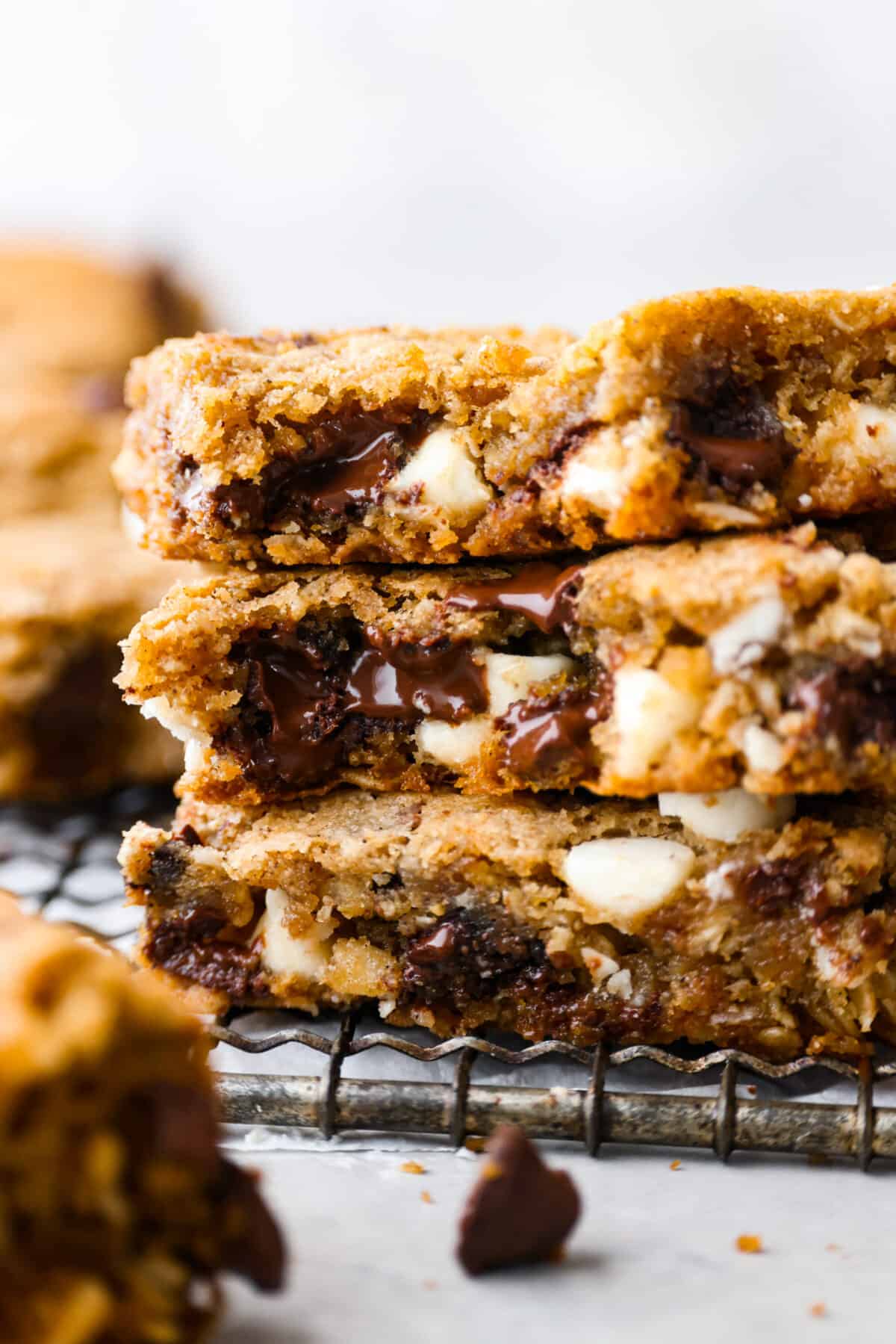 Win over everyoneโs heart (and stomach!) with these Marry Me Cookie Bars! They have the BEST flavor and texture, made with rolled oats, both white and semi-sweet chocolate chips, and a pinch of cinnamon! Chewy, creamy, chocolatey goodness! Closeup of 3 cookie bar slices. The melty white and semi sweet chocolate filling can be seen.