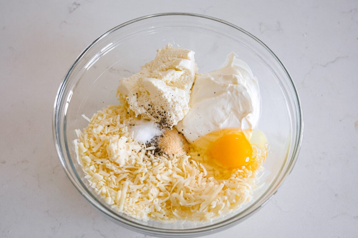 You will love the tasty flavors in this Monterey spaghetti! Tender spaghetti baked in a cheesy mixture and loaded with spinach and crispy fried onions. It's a surprisingly delicious combination of flavors and an easy weeknight dinner! Third process photo of the cheese, sour cream, egg, and ricotta cheese added to a bowl.