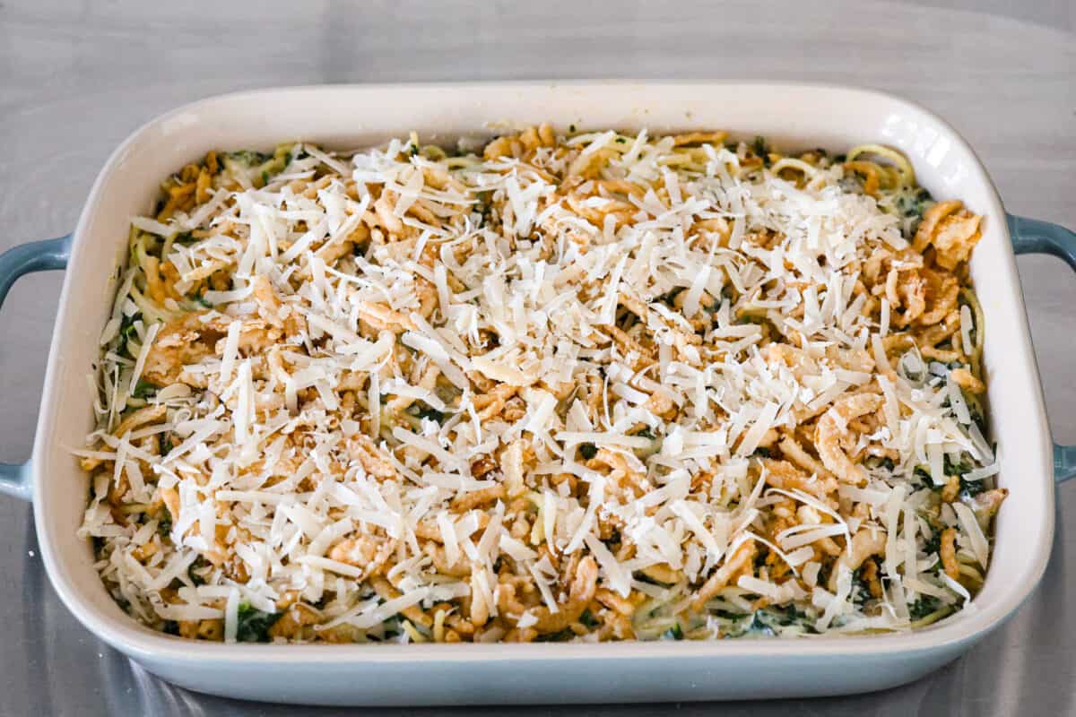 You will love the tasty flavors in this Monterey spaghetti! Tender spaghetti baked in a cheesy mixture and loaded with spinach and crispy fried onions. It's a surprisingly delicious combination of flavors and an easy weeknight dinner! Fourth process photo of Monterey spaghetti added to a baking dish before baking.