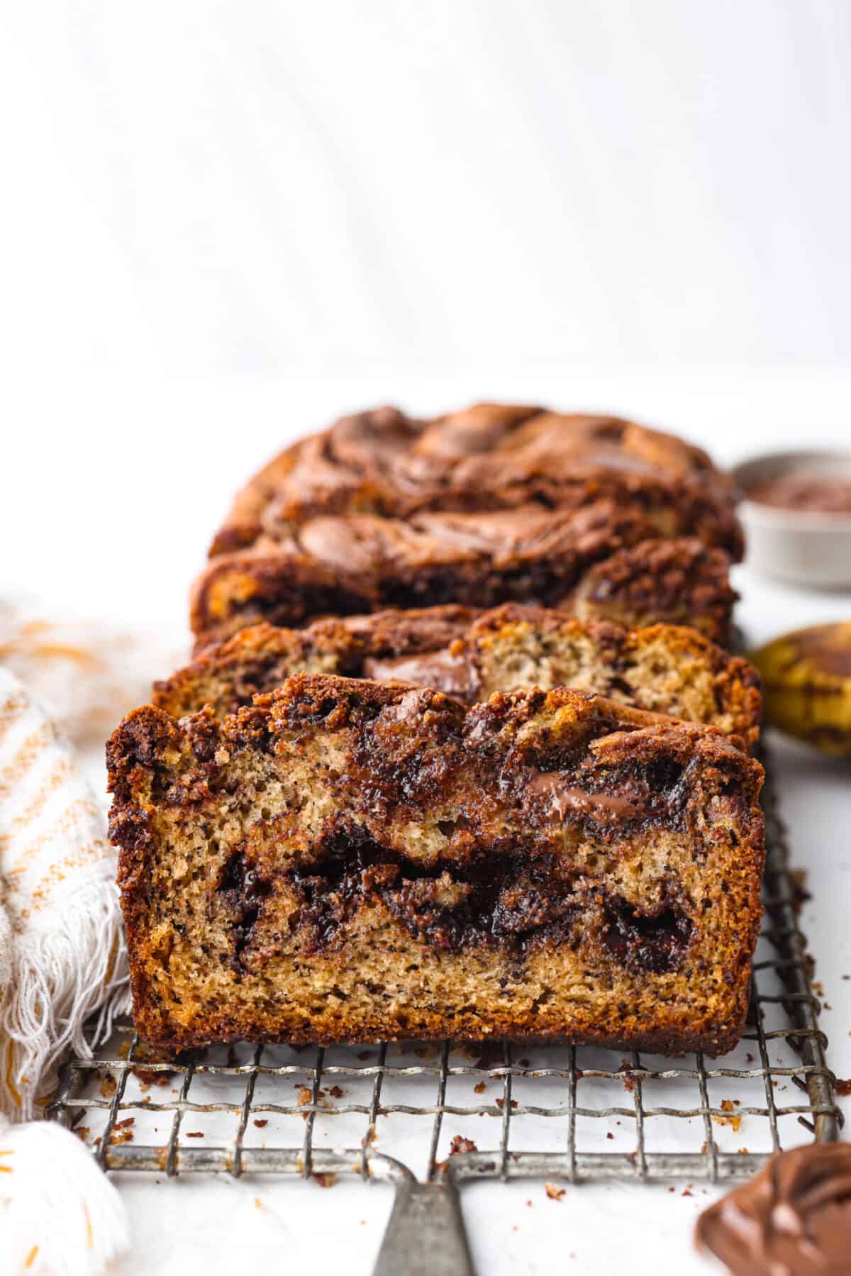 Treat yourself to the most incredible flavor and texture of this Nutella banana bread. One bite and you will be obsessed with the moist, tender crumb and how wonderful this quick bread tastes. It's a great way to use up ripe bananas and perfect for any occasion! Nutella banana bread, cut into slices.