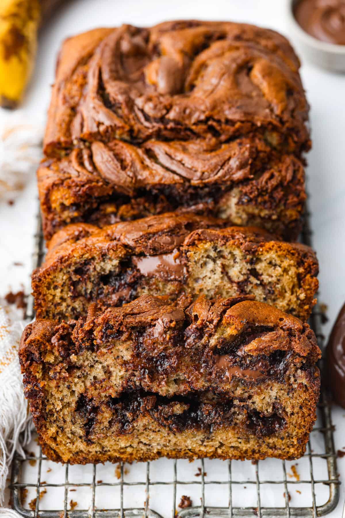 Treat yourself to the most incredible flavor and texture of this Nutella banana bread. One bite and you will be obsessed with the moist, tender crumb and how wonderful this quick bread tastes. It's a great way to use up ripe bananas and perfect for any occasion! Closeup of sweet bread, swirled with chocolate hazelnut spread.