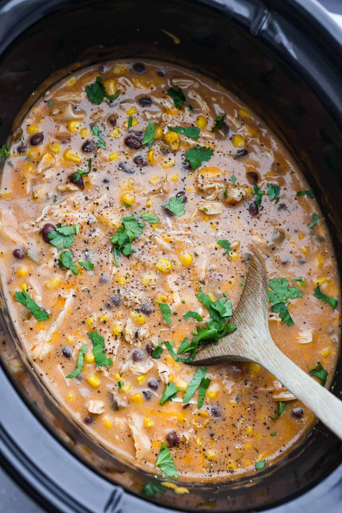 Everything you love about fajitas comes together in this hearty Slow Cooker Chicken Fajita Soup. Tender chicken surrounded by beans, corn, and spices simmers all day to perfection Chicken fajita soup in a slow cooker being stirred with a wooden spoon.