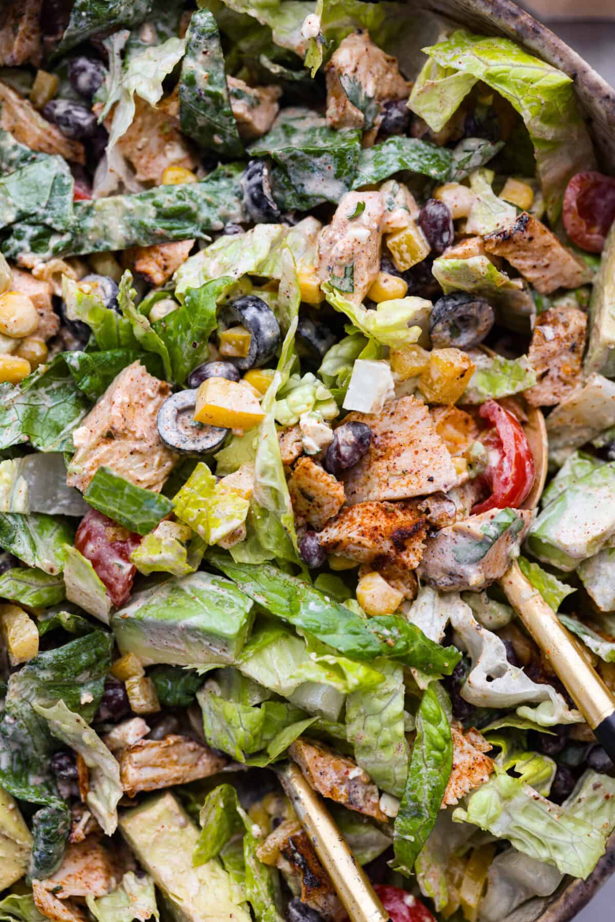This creamy Southwest dressing is packed with zesty lime and bold spices, ready to upgrade your favorite bowl of greens! It takes less than 10 minutes and only a few pantry staples to make. Santa fe salad in a large salad bowl, being tossed.