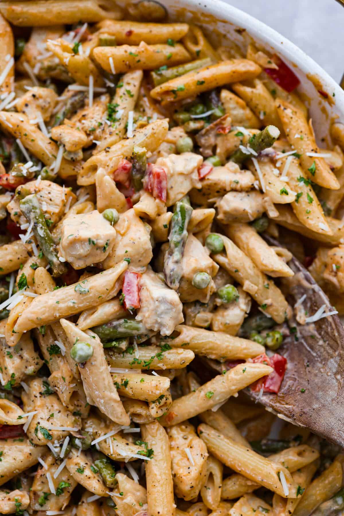Spicy chicken chipotle pasta is so creamy and rich with a spicy kick that you won't be able to get enough of. The warm, smoky flavor of the chipotle peppers balanced with a flavorful cream sauce is sure to delight your tastebuds! It is a mouthwatering entree that everyone will love! Inspired by Cheesecake Factory, this homemade version is so tasty! Closeup of the chipotle pasta being stirred with a wooden spoon.