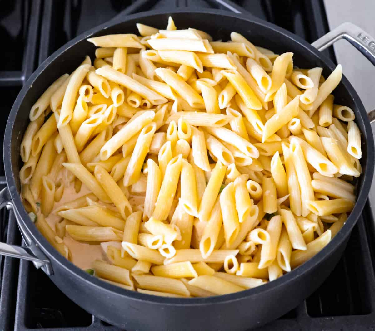 Spicy chicken chipotle pasta is so creamy and rich with a spicy kick that you won't be able to get enough of. The warm, smoky flavor of the chipotle peppers balanced with a flavorful cream sauce is sure to delight your tastebuds! It is a mouthwatering entree that everyone will love! Inspired by Cheesecake Factory, this homemade version is so tasty! Stirring in the cooked penne pasta.
