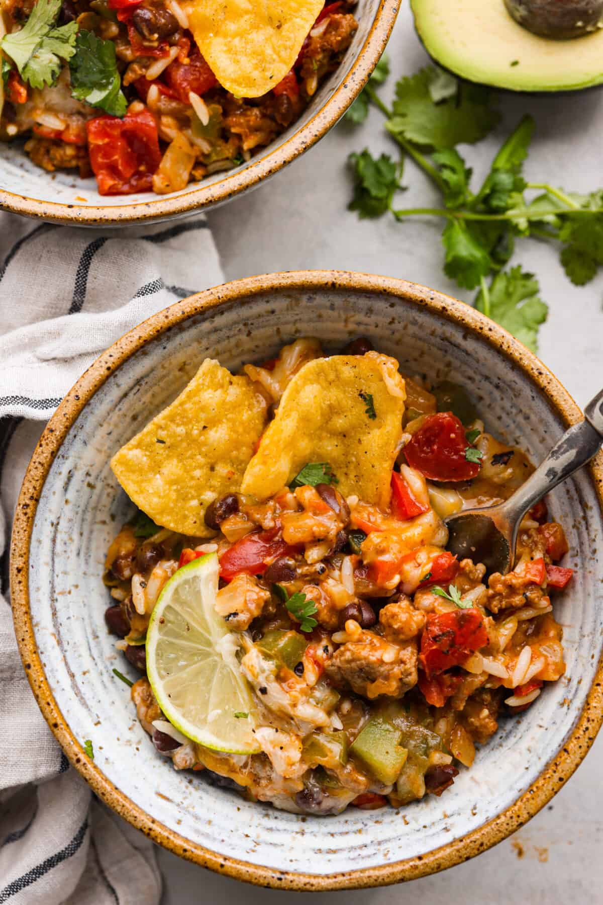 Okay, but can we talk about how gorgeous this taco skillet is?! Like, if dinner could be a showoff, this would be it. Itโs giving melty, cheesy, golden perfection, and the best part? It all comes together in one pan. A serving of the taco skillet in a stoneware bowl topped with tortilla chips and a lime slice.