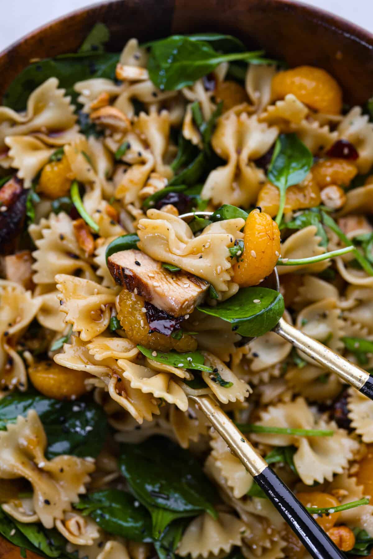 Teriyaki spinach pasta salad combines juicy mandarin oranges, savory teriyaki chicken, and crunchy cashews for a flavor explosion in every bite! The best Asian-inspired pasta salad to serve alongside your favorite meals. Closeup of a serving of pasta salad.