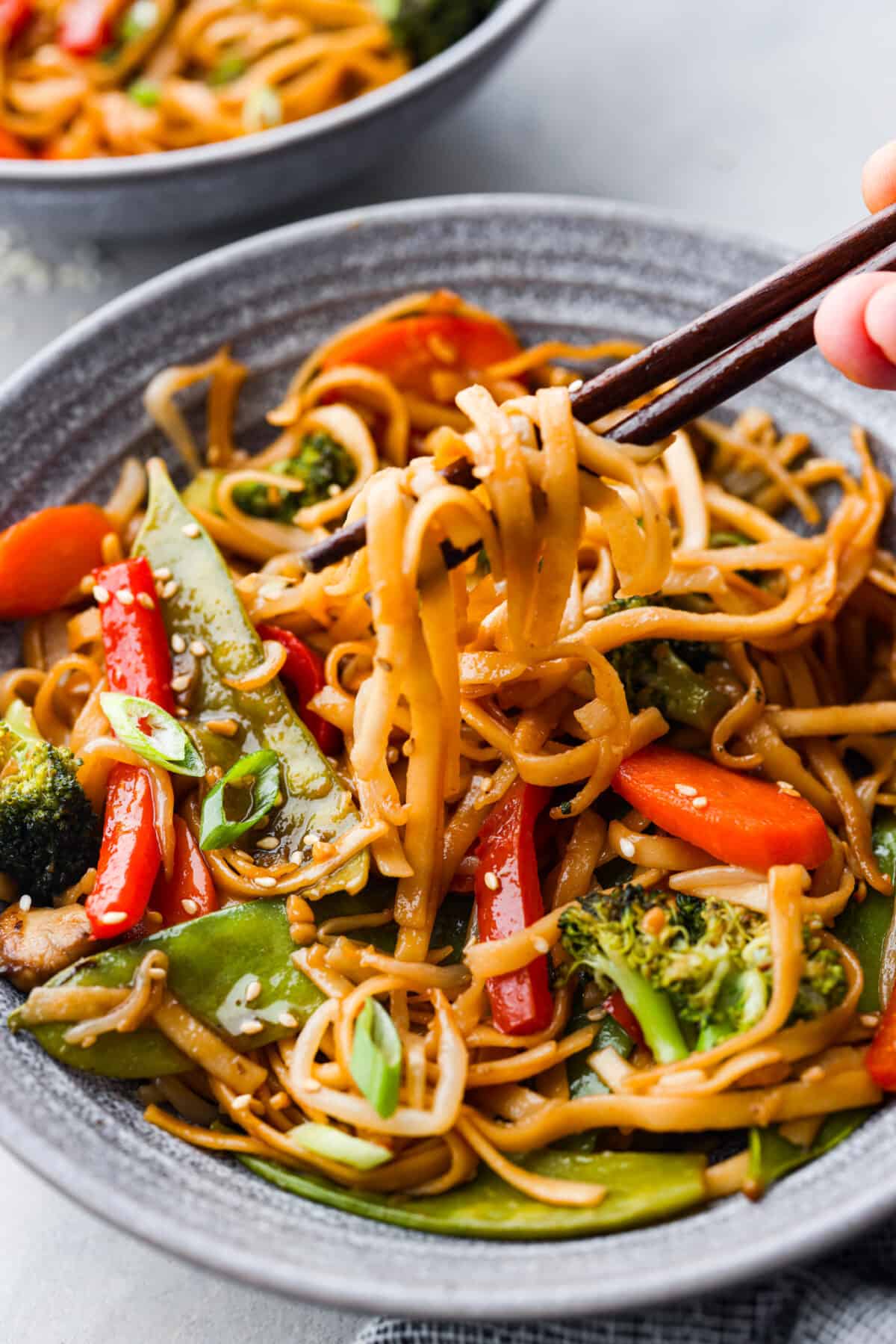 20-minute Vegetable Lo Mein is a super easy weeknight dish loaded with fresh, stir-fried veggies! Picking up noodles with chopsticks.