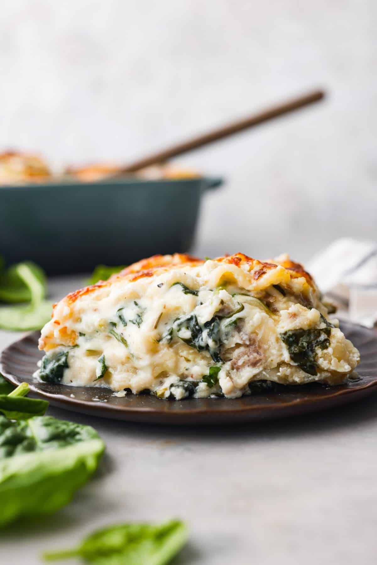 This white lasagna recipe swaps out traditional marinara for a homemade alfredo sauce that’s too good to resist. Packed with tender spinach, ricotta cheese, and Italian sausage, each bite is a dream! A serving of white lasagna on a small plate.
