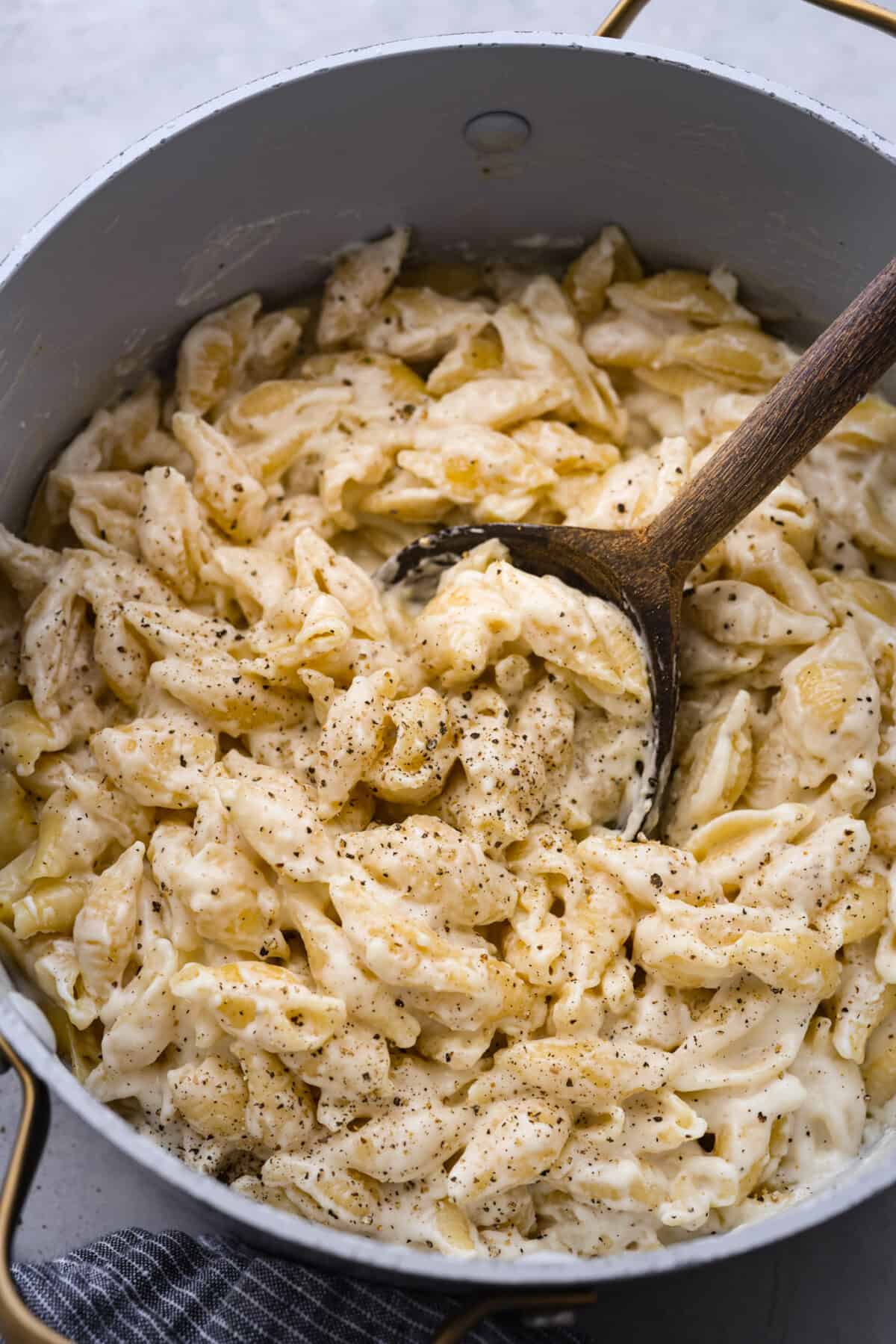 White Cheddar Mac and Cheese is super creamy and filled with rich, decadent flavor. This pasta recipe is the perfect comforting side dish for potlucks, holidays or even weeknight dinners! White cheddar mac and cheese in a large pot.