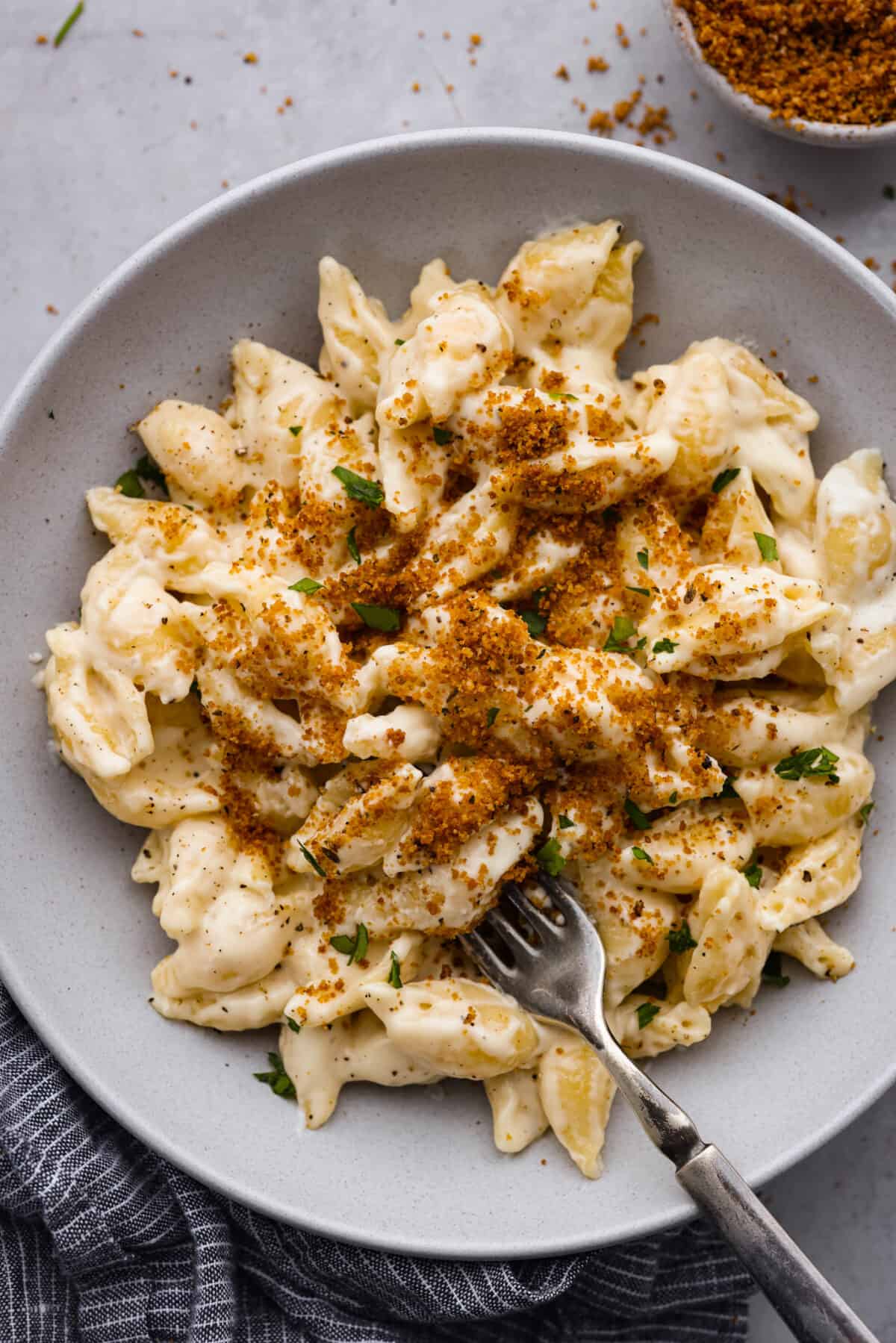 White Cheddar Mac and Cheese is super creamy and filled with rich, decadent flavor. This pasta recipe is the perfect comforting side dish for potlucks, holidays or even weeknight dinners! A serving of mac and cheese, topped with breadcrumbs.