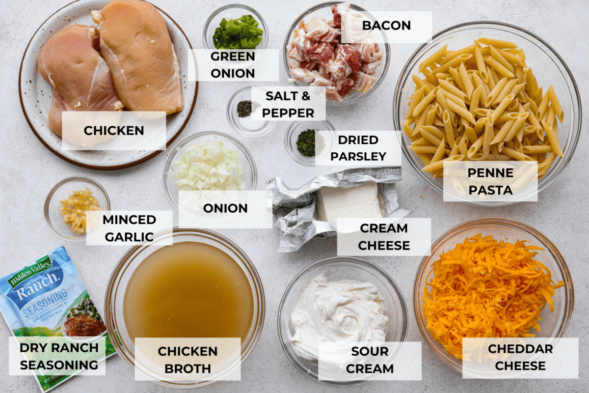 Cheesy, creamy, and loaded with ranch flavor and chunks of juicy chicken, 'Crack Chicken' pasta is a dinner that will have everyone raving! And as if you needed more reason to make it, it's ready in 30 minutes from start to finish! All of the crack chicken pasta ingredients laid out in glass bowls. Listed are: chicken, green onion, bacon, salt and pepper, dried parsley, penne pasta, minced garlic, onion, cream cheese, dry ranch seasoning, chicken broth, sour cream, and cheddar cheese.