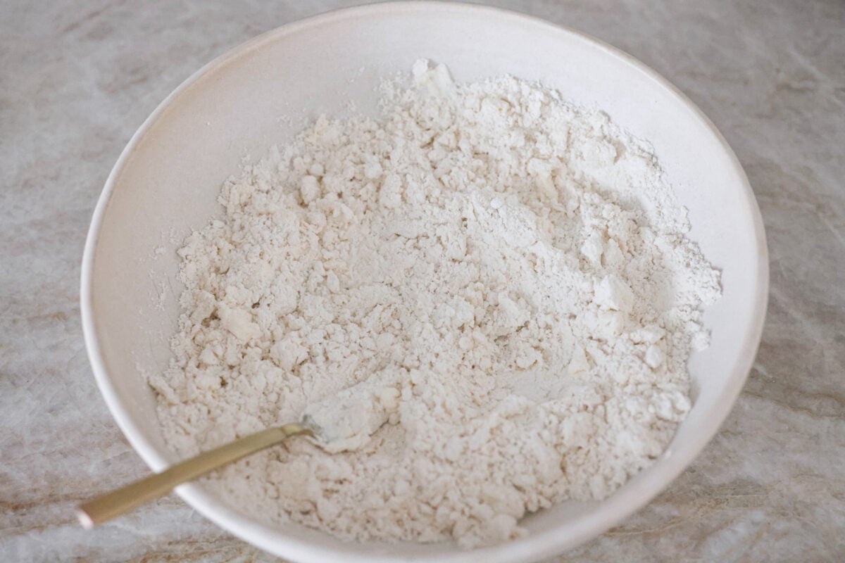 Tender and fluffyย 7-up biscuitsย rise to perfection and instantly become everyone's favorite biscuit! It only takes 4-ingredients to create this melt-in-your-mouth biscuit recipe! First process photo of the sour cream cutting into the Bisquick.