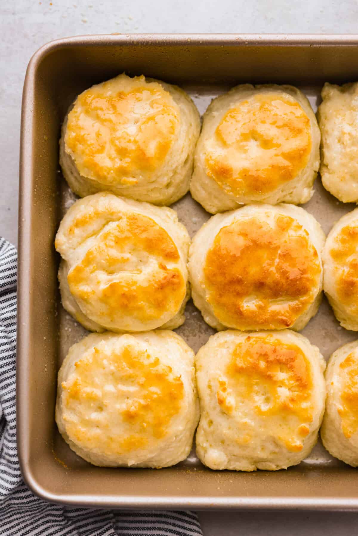 Tender and fluffyย 7-up biscuitsย rise to perfection and instantly become everyone's favorite biscuit! It only takes 4-ingredients to create this melt-in-your-mouth biscuit recipe! Top view of the baked 7 up biscuits in a baking pan.