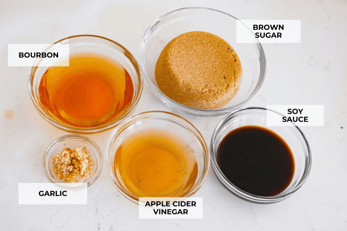 This delicious bourbon marinade will add wonderful depth of flavor and tenderize any meat you're cooking, from steak to chicken! This recipe uses ingredients like brown sugar, Worcestershire sauce, apple cider vinegar, garlic and bourbon to infuse each piece of meat with the perfect savory, sweet and tangy flavor. All of the marinade ingredients in separate glass bowls.