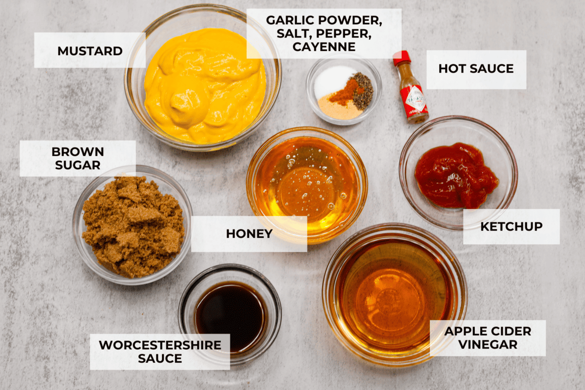 Smoky, tangy, and sweet, your taste buds will be begging you for more of this Mustard BBQ Sauce! It's the perfect addition to your summer cookouts this year, adding the best flavor to grilled meats! All of the ingredients for the sauce separated into individual glass bowl. Listed are: mustard, garlic powder, salt, pepper, cayenne, hot sauce, brown sauce, honey, ketchup, worcestershire sauce, and apple cider vinegar.