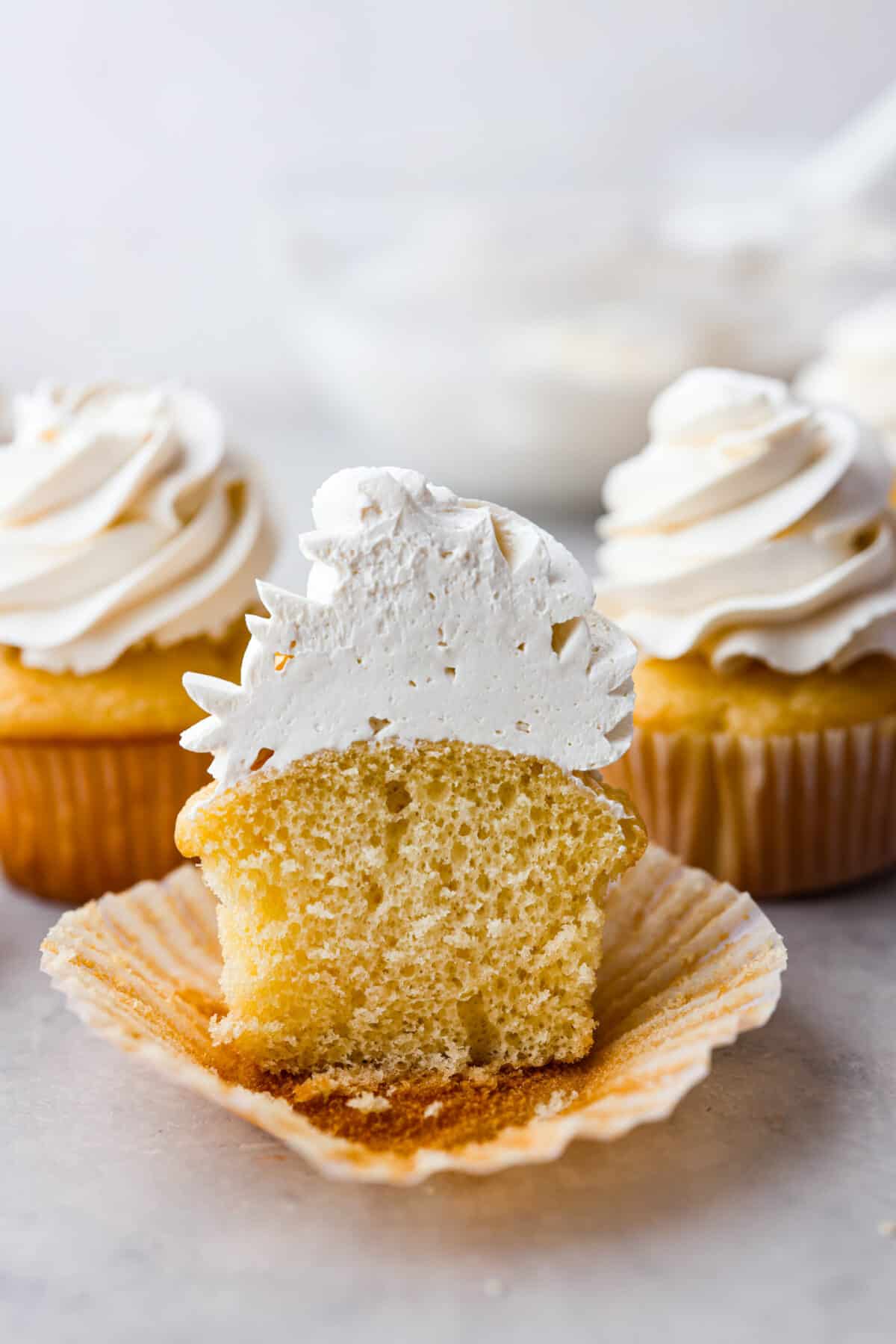 The most delicious Swiss Meringue Buttercream is easy to make with just 5 simple ingredients! It whips up deliciously light and silky with the right amount of sweetness. The perfect finishing touch for all of your favorite treats! A cupcake frosted with Swiss meringue buttercream, cut in half.