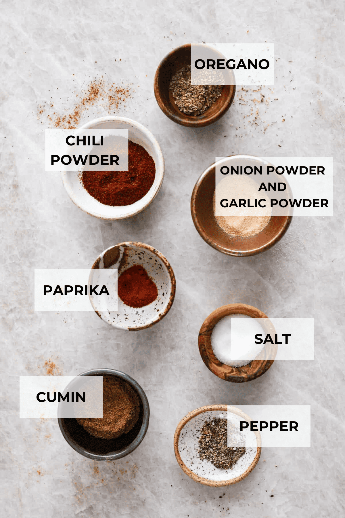 This Homemade Taco Seasoning is so flavorful and takes less than 5 minutes to make. You will never buy taco seasoning from the store again! The top view of ingredients, each in separate bowls and labeled with what is in them.