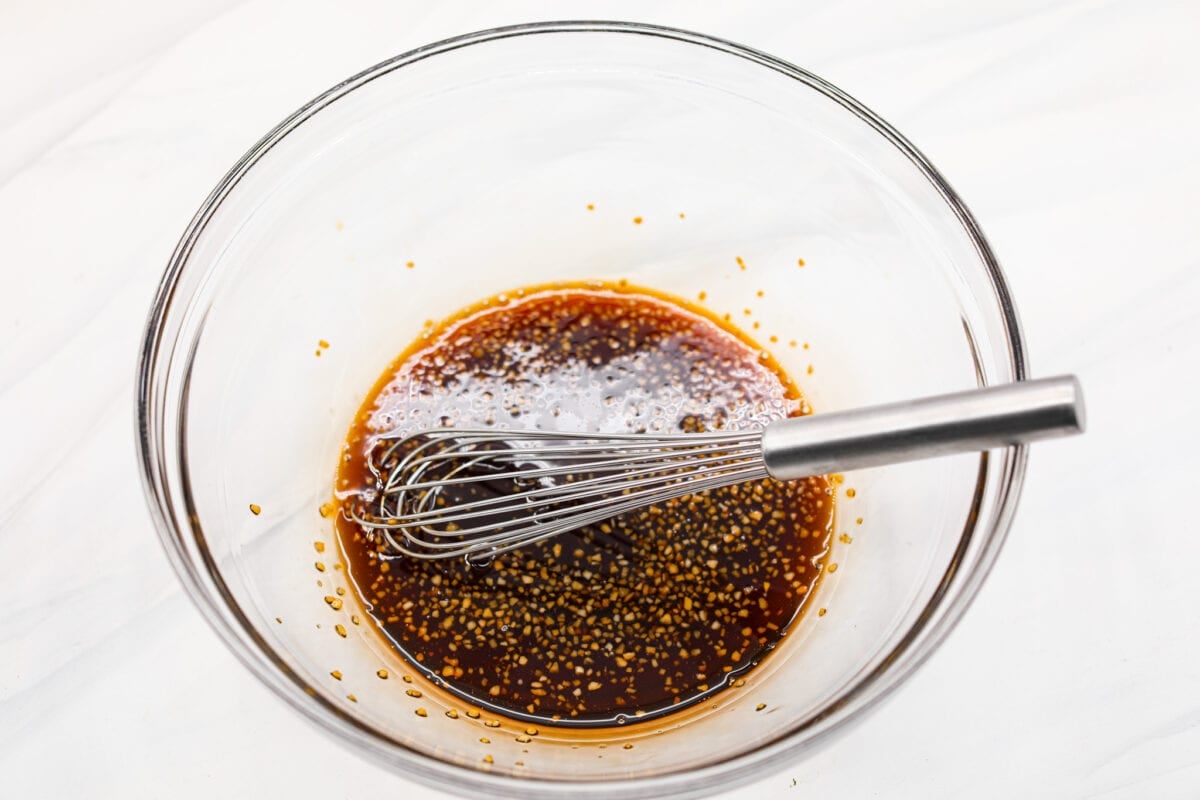 Cooked in less than 10 minutes, these perfectly glazed honey garlic air fryer salmon bites are so delicious. This is such a quick dinner, you will never want to cook salmon any other way! A bowl of marinade with a whisk.