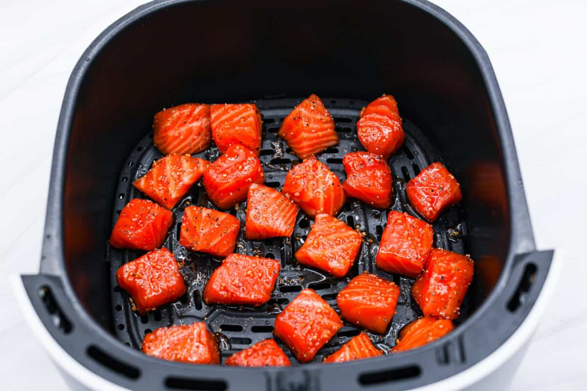 Cooked in less than 10 minutes, these perfectly glazed honey garlic air fryer salmon bites are so delicious. This is such a quick dinner, you will never want to cook salmon any other way! Salmon bites in the air fryer basket ready to cook.