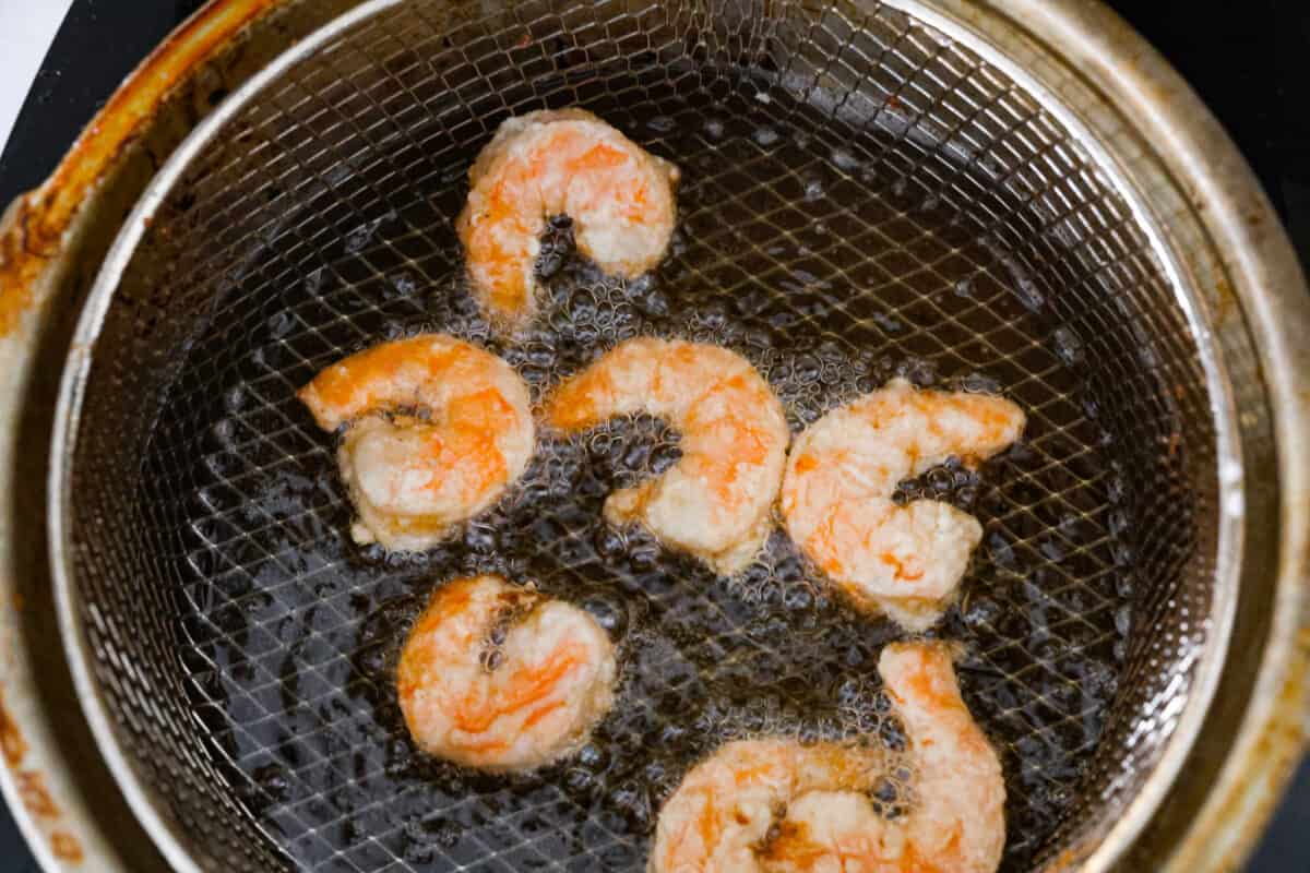 These Bang Bang Shrimp Tacos are made with deliciously crunchy shrimp cooked to perfection and coated in a special sauce that's just bursting with flavor! It's a meal that's sure to impress. Shrimp being cooked in oil.