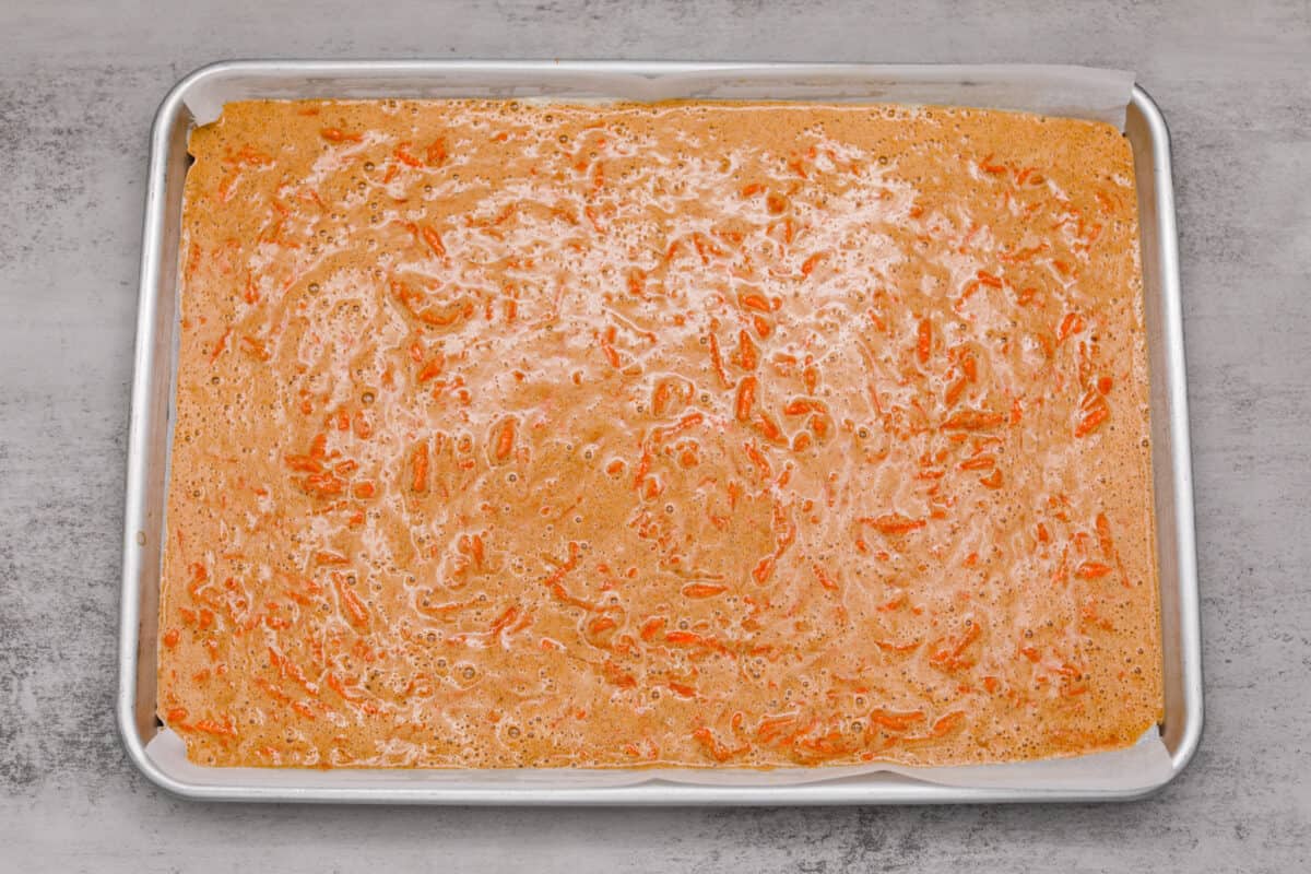 Stunning carrot cake roll is a wonderful joining of deliciously spiced carrot cake, swirled with tangy cream cheese frosting. It looks fancy but it's easy to make and so perfect for Easter and Spring themed celebrations! Batter poured into a baking dish.