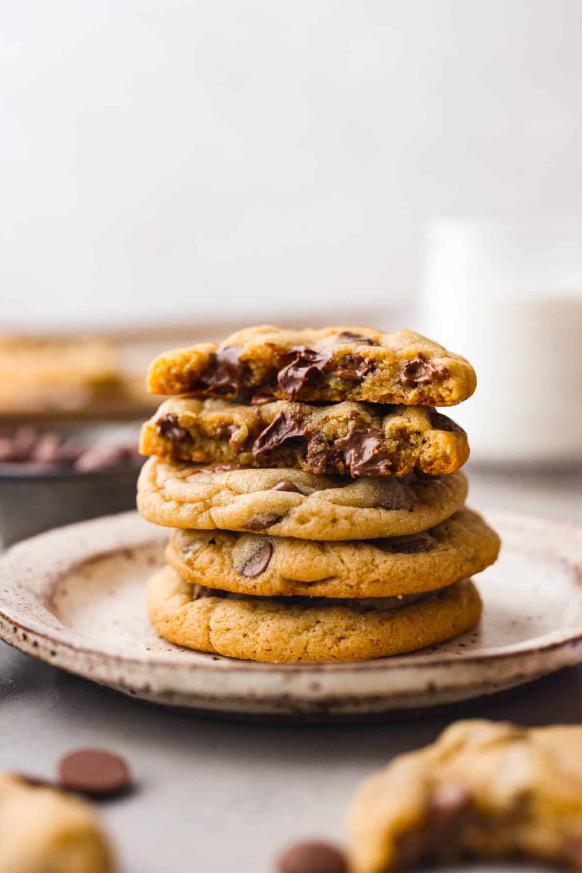 Introducing the softest and chewiest chocolate chip pudding cookies to ever come out of your oven! Adding Instant pudding mix creates the perfect cookie that dreams are made of. Close side view of chocolate chip pudding cookies stacked on a plate with the top two cookies bitten into.
